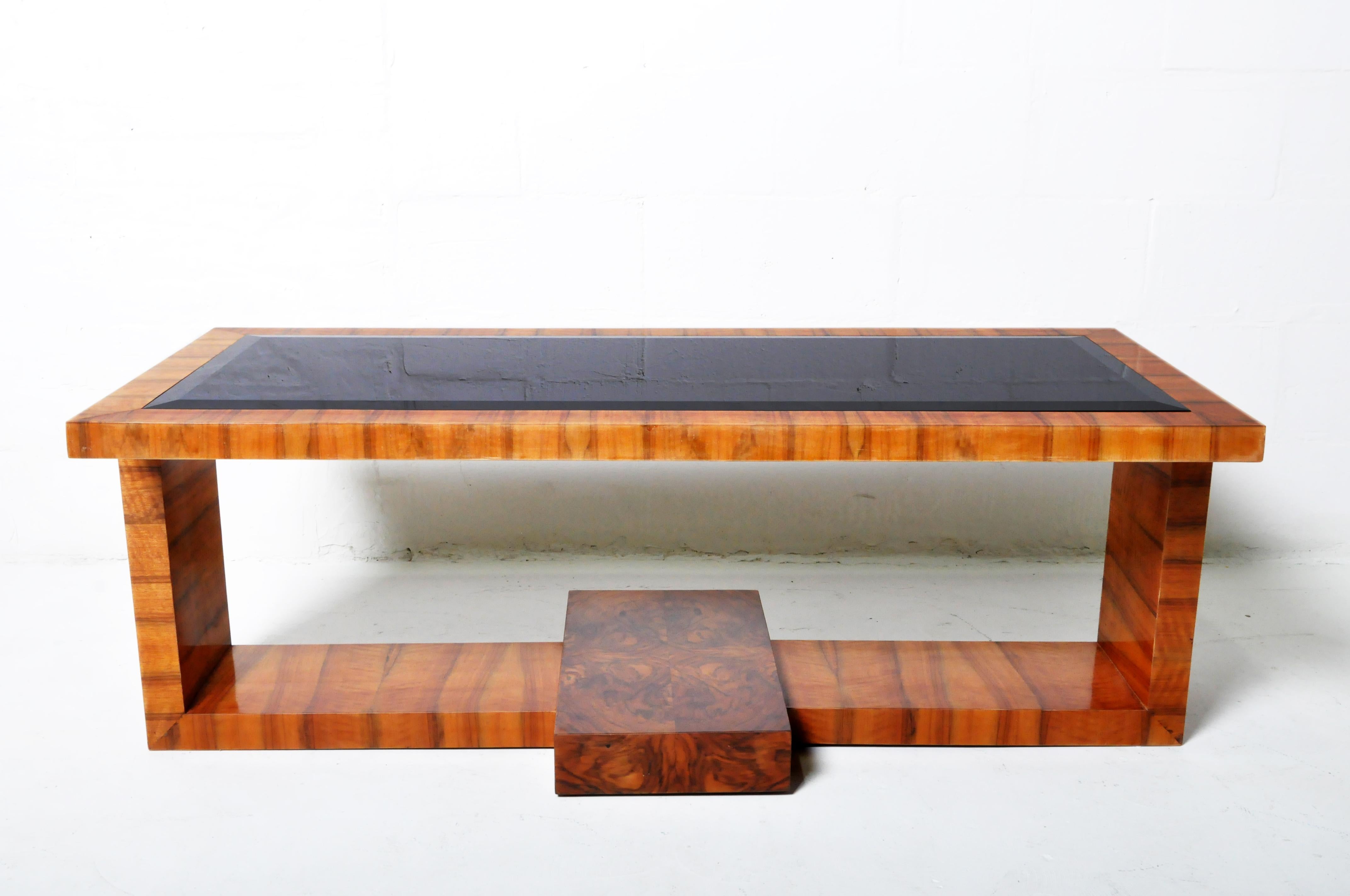 A modern French Art Deco-inspired coffee table in striking walnut veneer and with a smoked glass top.