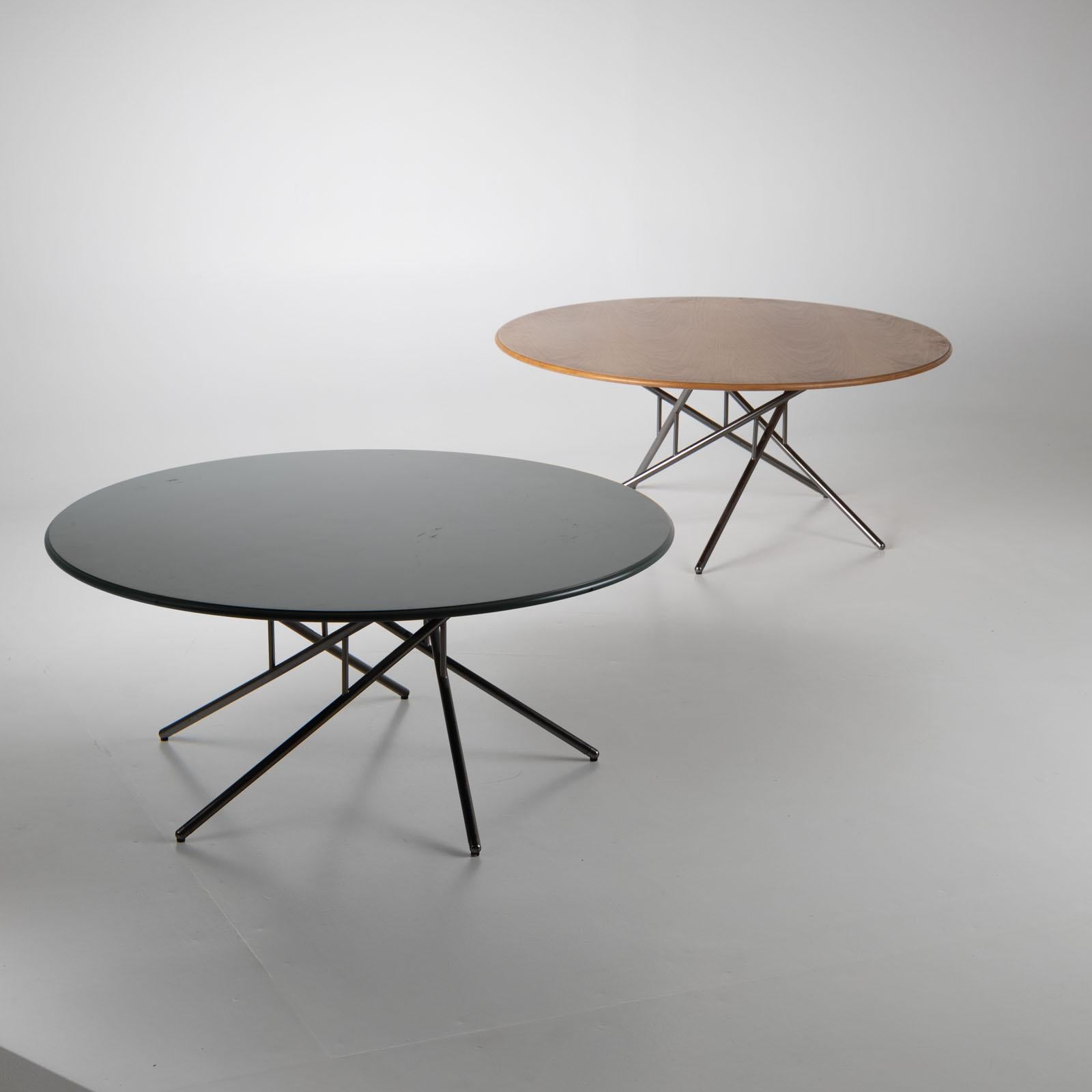 Pair of coffee tables on polished metal rod frames and round table tops. One table has a veneered wooden top, the other is laminated in dark green.  