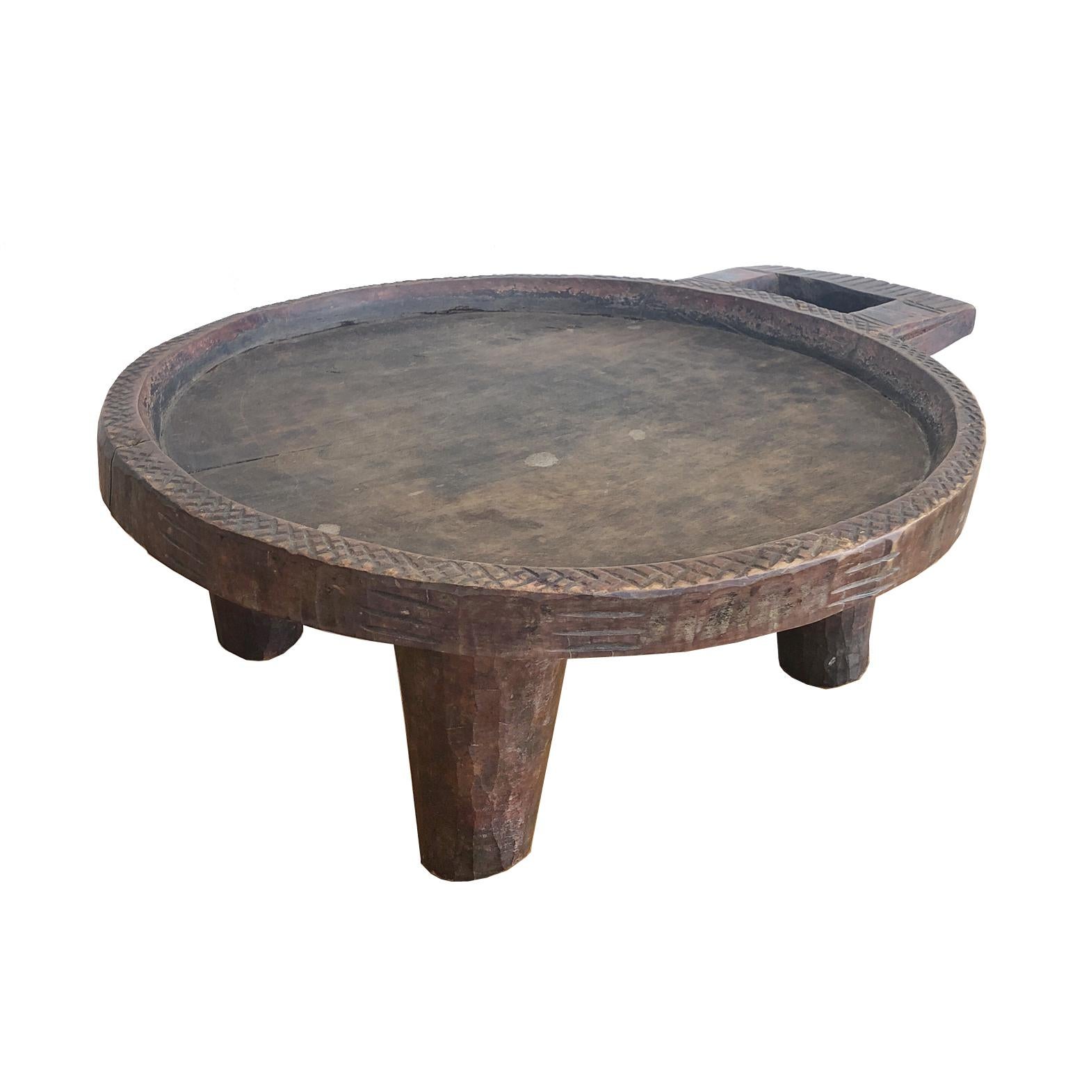An Ethiopian coffee tray carved out of a single piece of wood with round tray and handle resting on four legs, from the Gurage zone, named from the Gurage People. Incised geometric carvings embellish the border and handle. Gurage is a Zone in the