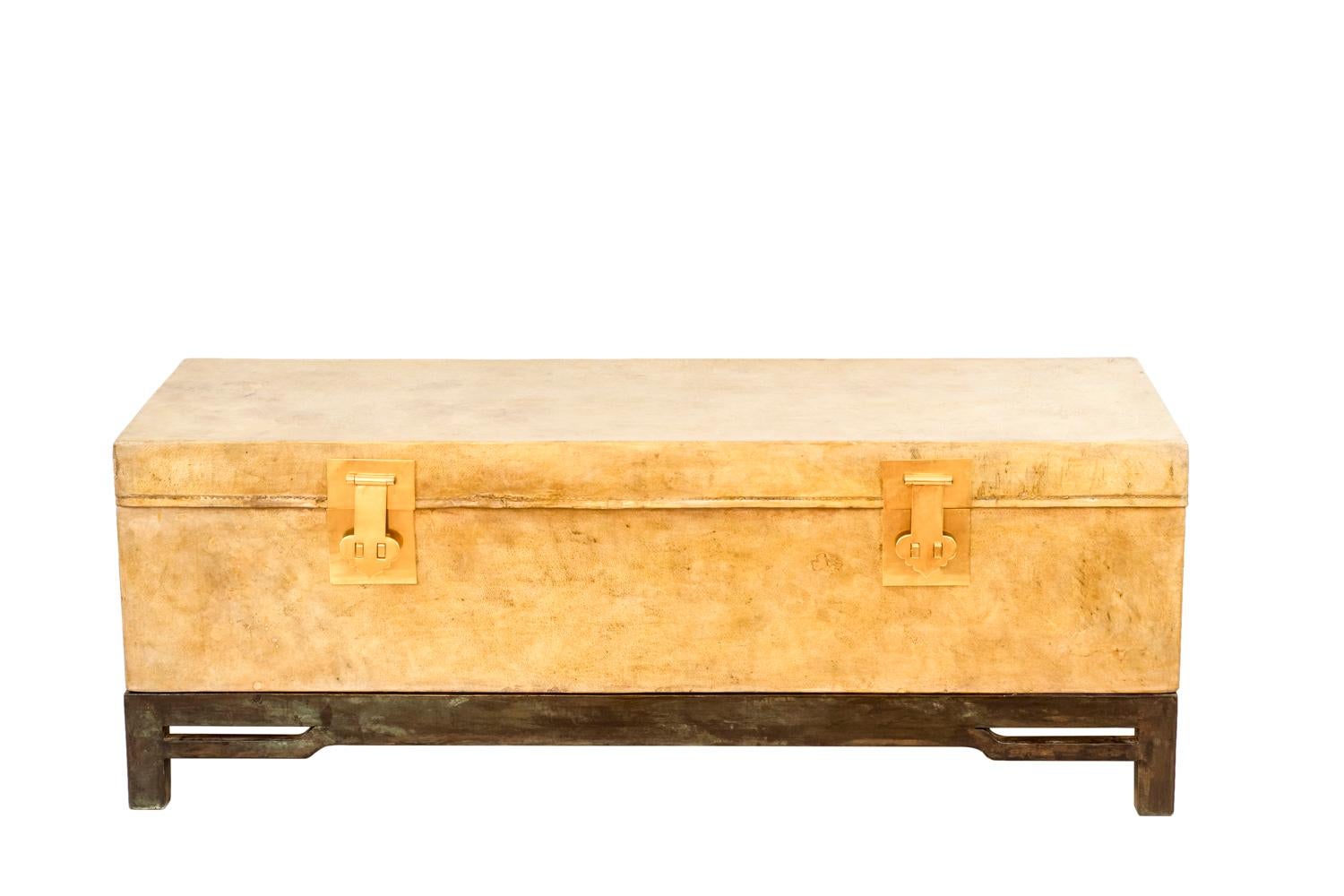 Rectangular shape coffer in cream parchment opening by a top flap, closed thanks to two gilt brass latches.
Interior in dark brown parchment.
It stands on a green-brown lacquered wood base with four square legs and an openwork apron.
Movable coffer