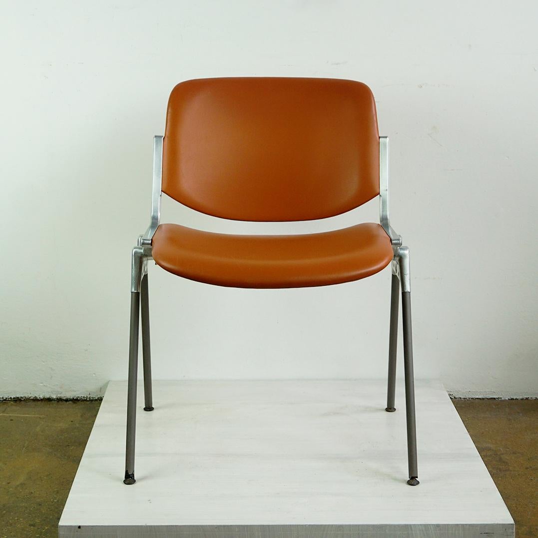 Questa iconica sedia impilabile italiana Midcentury Modern DSC 106 è stata disegnata nel 1965 da Giancarlo Piretti per Castelli Italy. La seduta e lo schienale in similpelle marrone cognac sono in ottime condizioni e presentano solo alcuni segni di