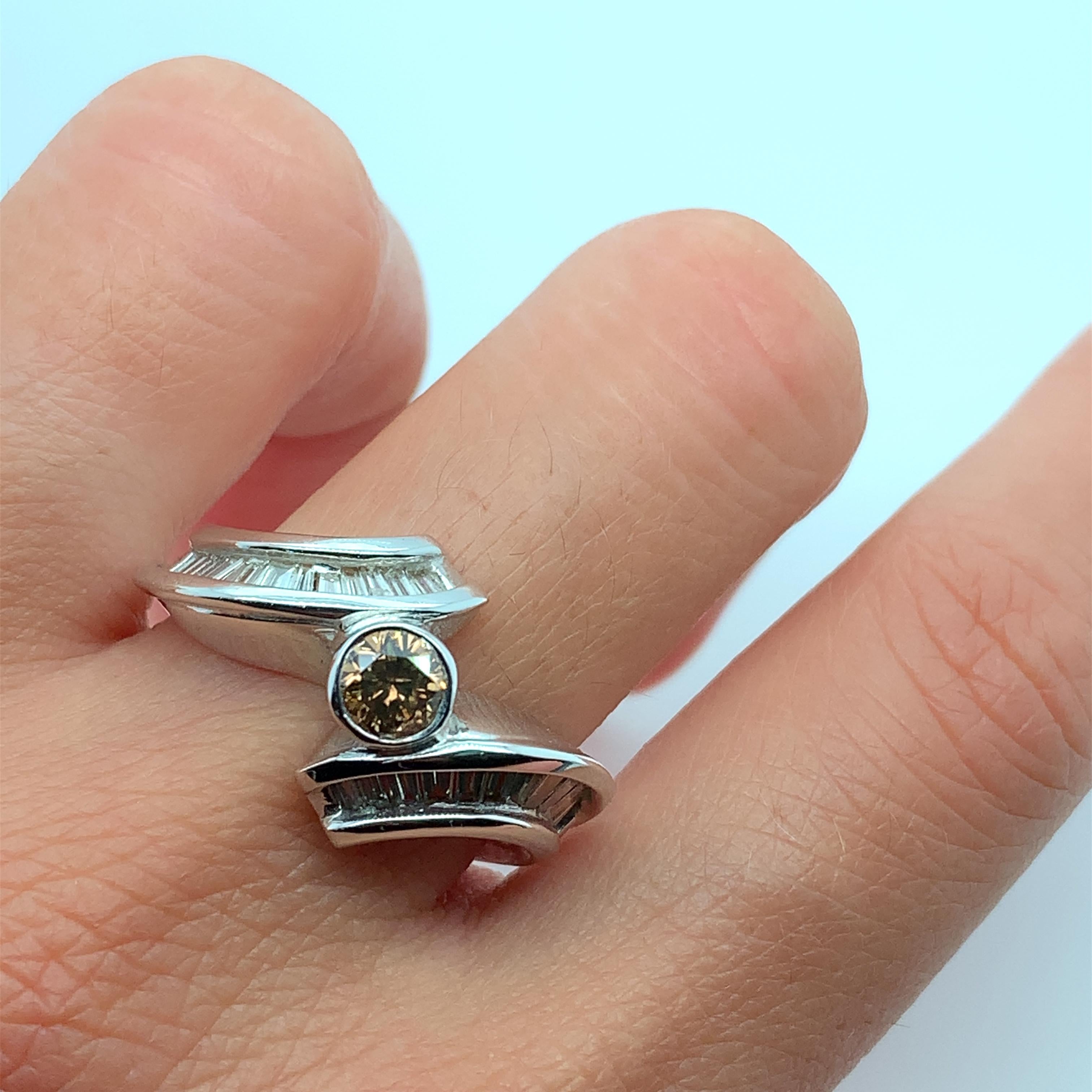1.10ct Chocolate Brown Cognac diamond and baguette diamonds engagement ring in 18k gold. Head twisted measuring approximately 13.5mm.
Solitaire 1.10ct brown diamond round shaped with baguette diamonds twist style engagement ring in 18ct white