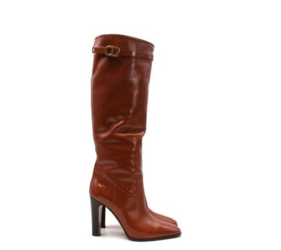 Dior Cognacbraune lange Lederstiefel mit Absatz
 

 - Glänzendes, braunes Oberleder
 - Abgerundete Zehenspitze und hoher Pfennigabsatz
 - Leicht gerafftes Bein, mit CD-Logo-Schnallenverschluss aus goldfarbenem Metall 
 - Ziehen Sie 
 

