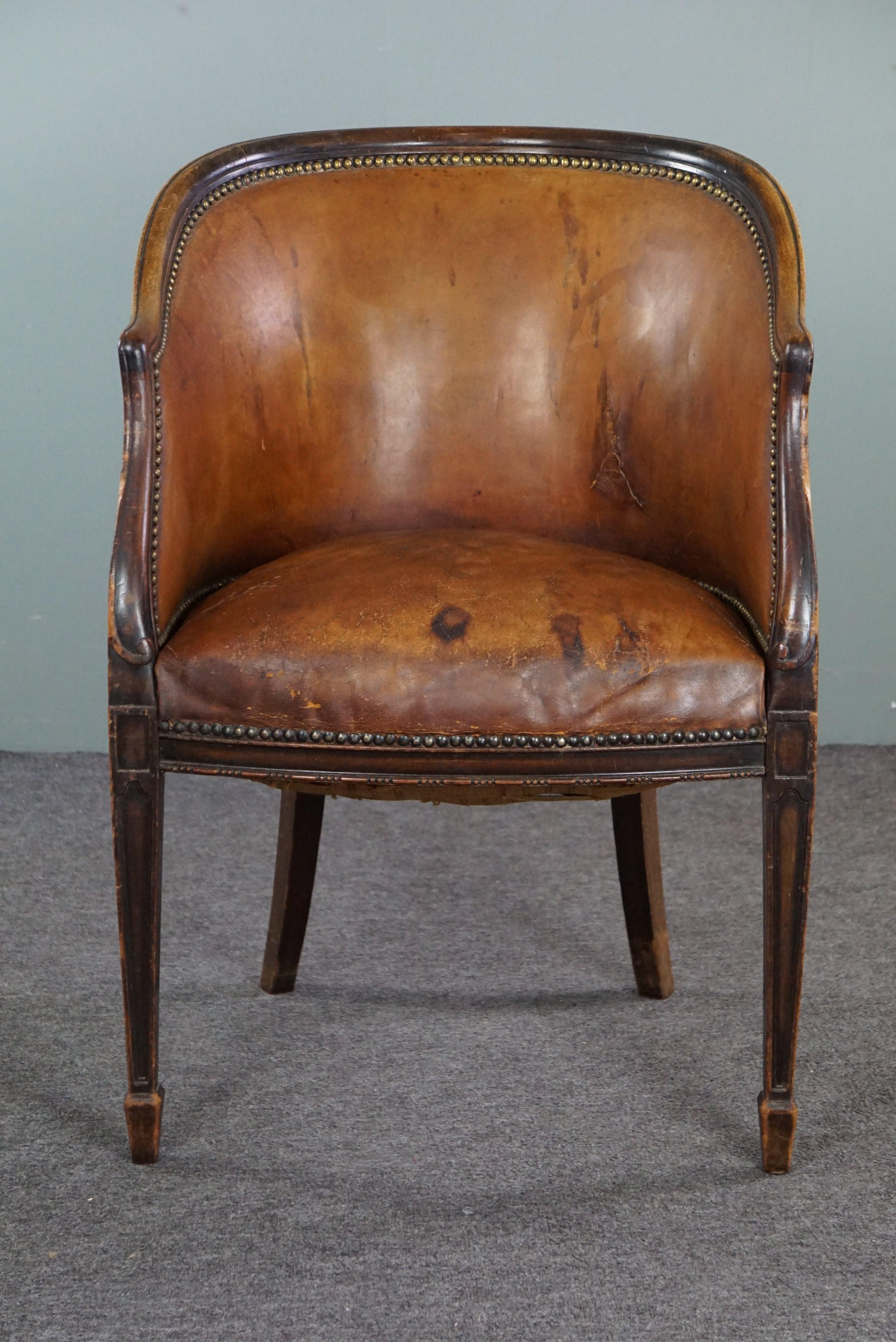 Offered is this antique leather tub chair with plenty of patina and character. 
Discover this extraordinary antique leather tub chair infused with character and a beautifully developed patina. Crafted from stunning cognac-colored leather, this chair