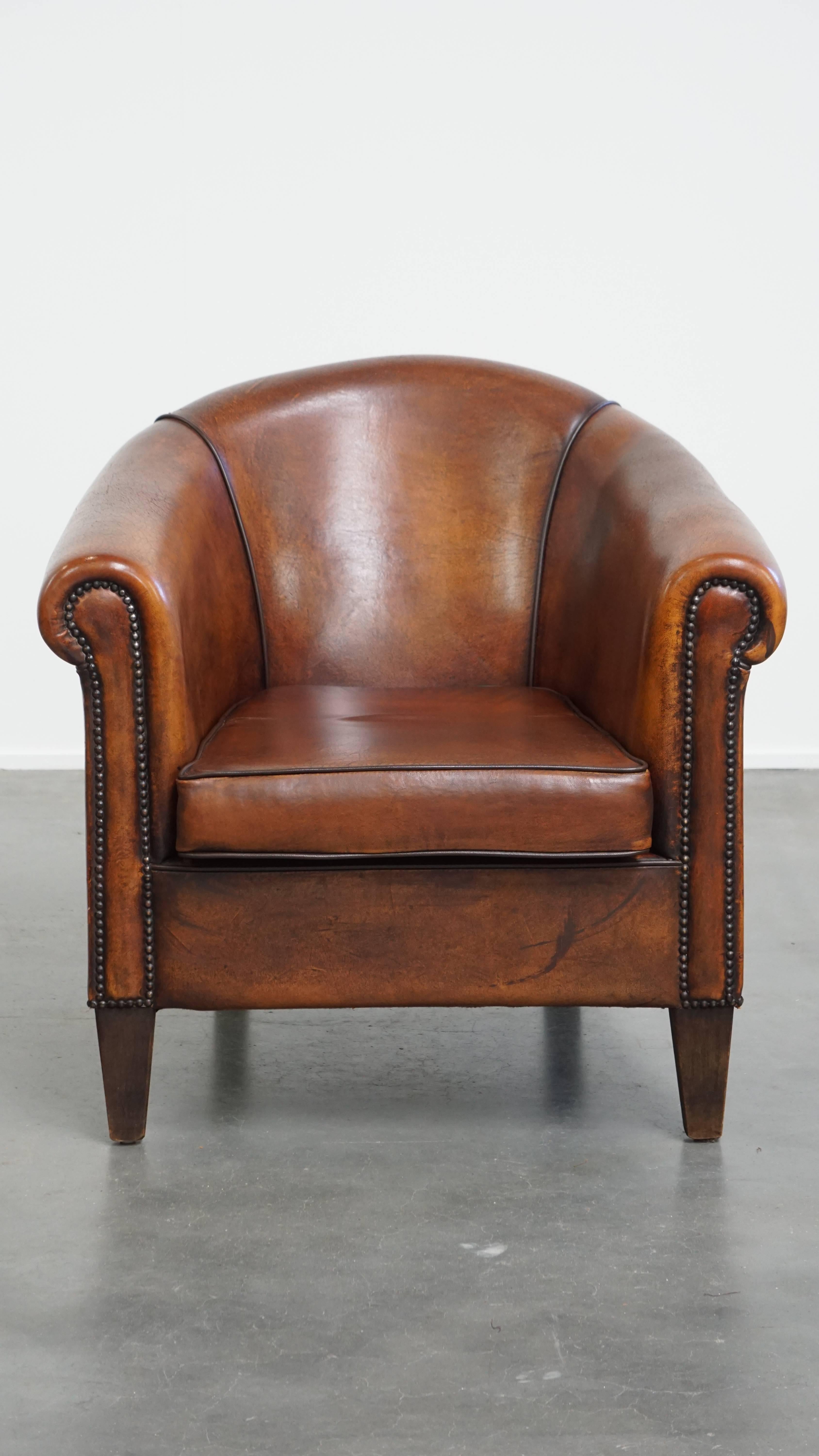 Nous vous proposons ce fauteuil club de caractère, de couleur cognac, en cuir de mouton avec une garniture de clous décorative. Ce fauteuil club en cuir de mouton de couleur cognac attire tous les regards dans presque tous les intérieurs et, à notre