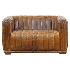 Cognac-colored cowhide 2-seater designer sofa finished with piping
