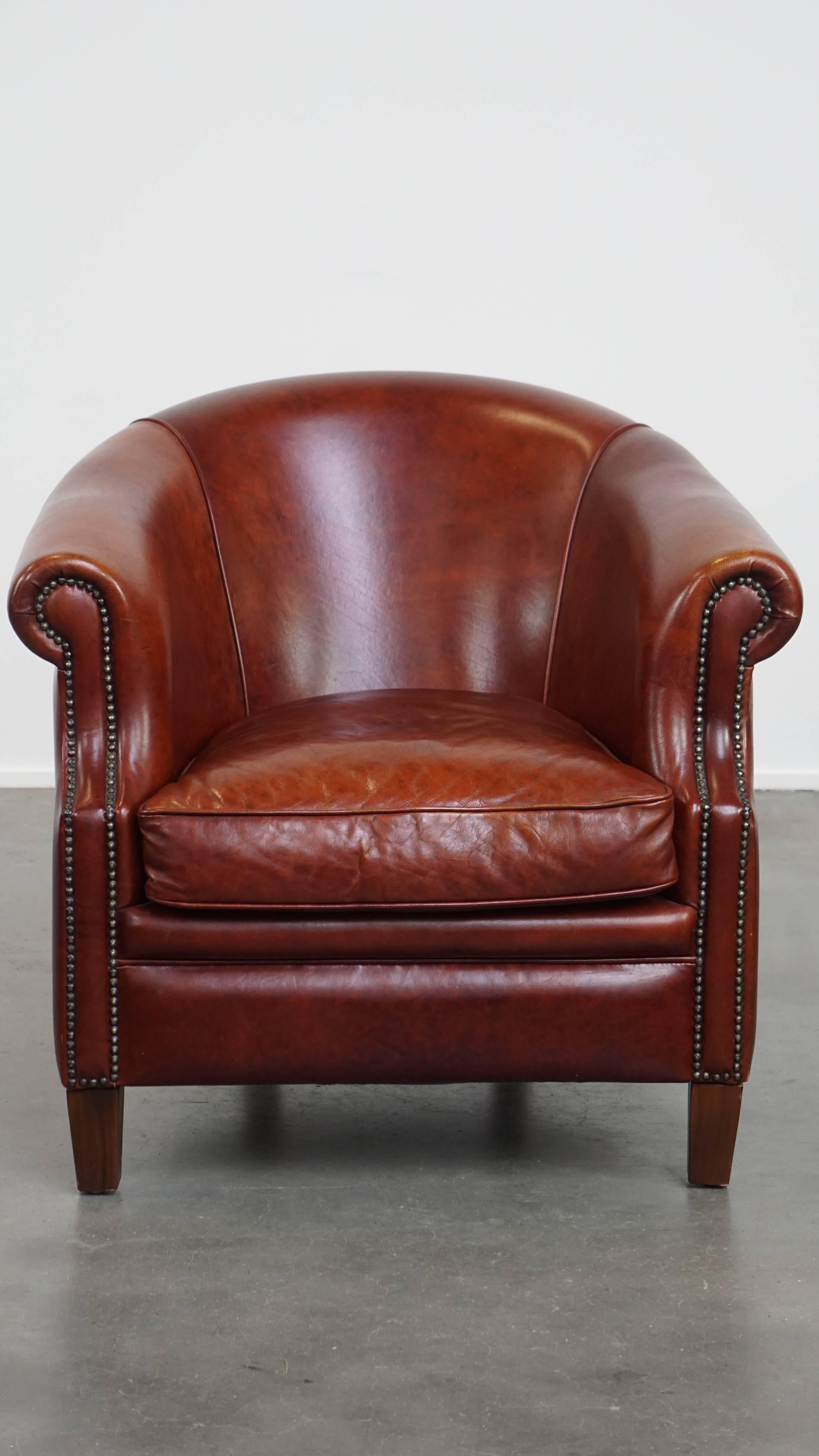 Offered here is this very beautiful cognac-colored cowhide leather club armchair in English style, tastefully finished with decorative studs. 

This timeless classic fits made of cowhide seamlessly into almost any interior and space. For example, it