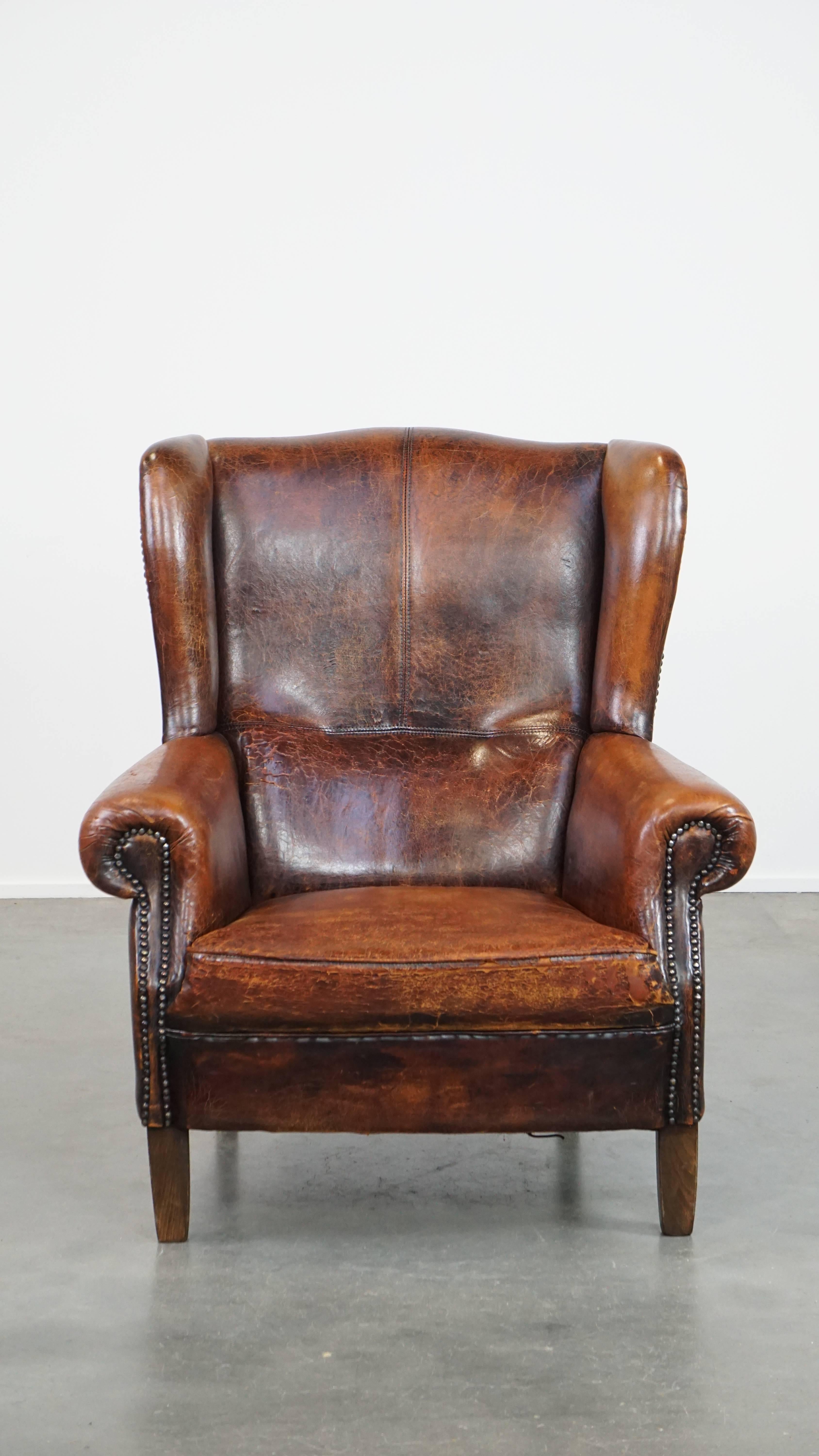 Dieser unglaubliche Ohrensessel aus Schafsleder im Vintage-Stil ist nicht nur charaktervoll, sondern auch äußerst bequem. Dieser große Ohrensessel ist in einem schönen Cognac-Ton gehalten, mit Ziernägeln versehen und strahlt einen Hauch englischer