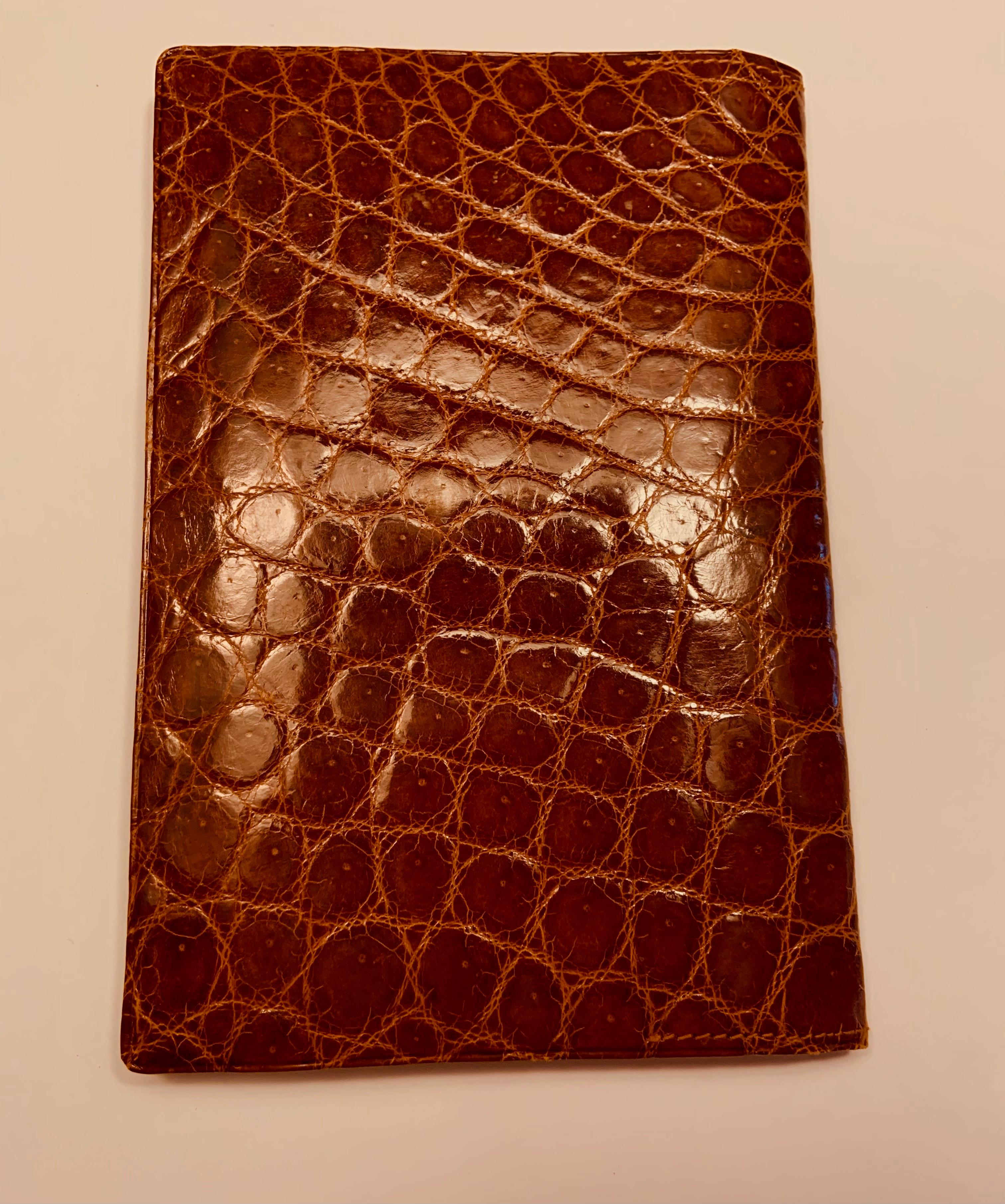 A glazed brown crocodile exterior is matched to a brown fine leather interior. There is a coin purse and two open, silk lined  compartments on one side. The other side has two large silk lined sections and two smaller silk lined sections
 for