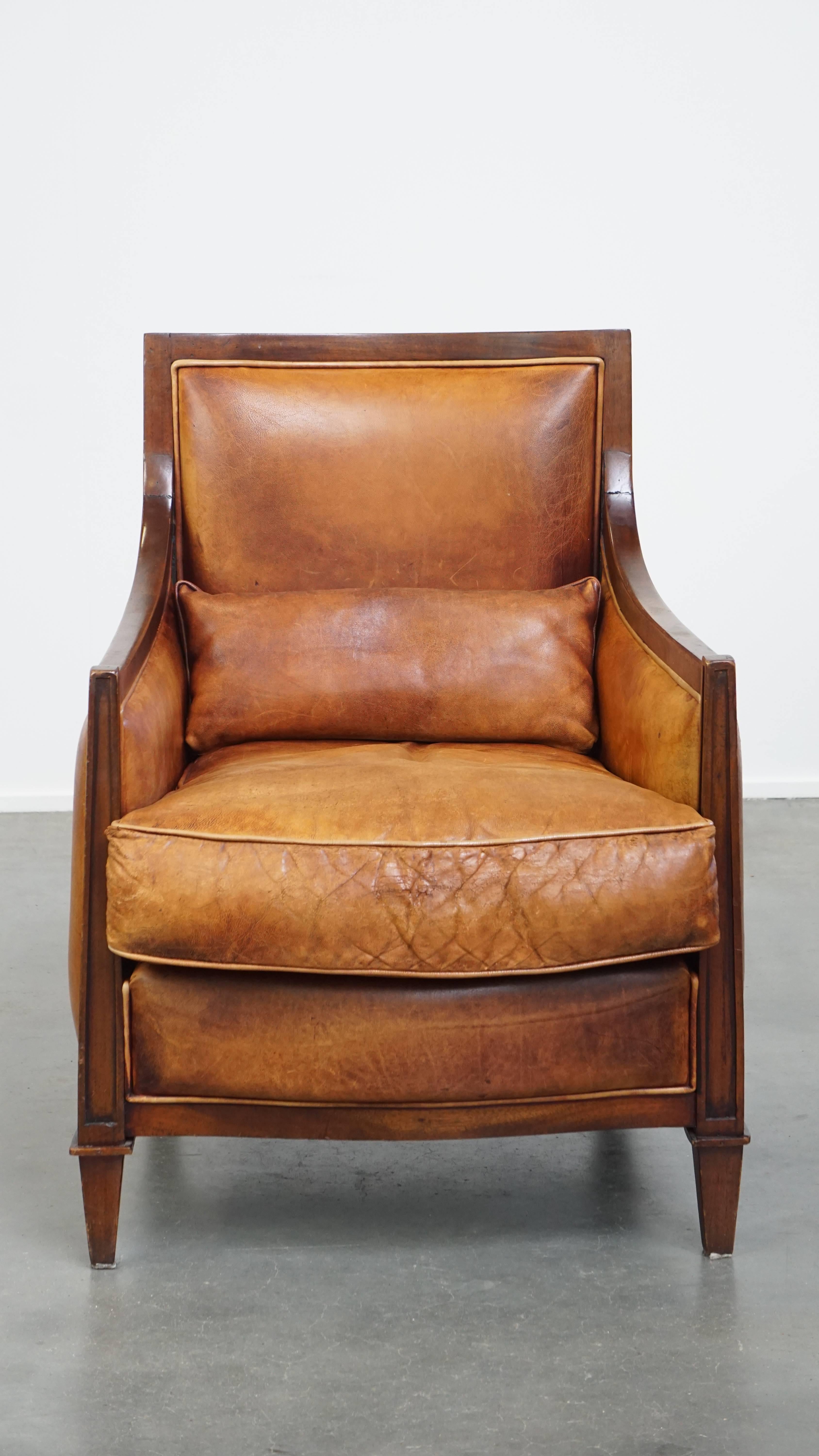 Offered here is this beautiful cognac-colored sheepskin leather Art Deco design armchair, combined with wood. 

This armchair is full of character, and thanks to its timeless Art Deco design, it fits effortlessly into nearly any interior. It is made