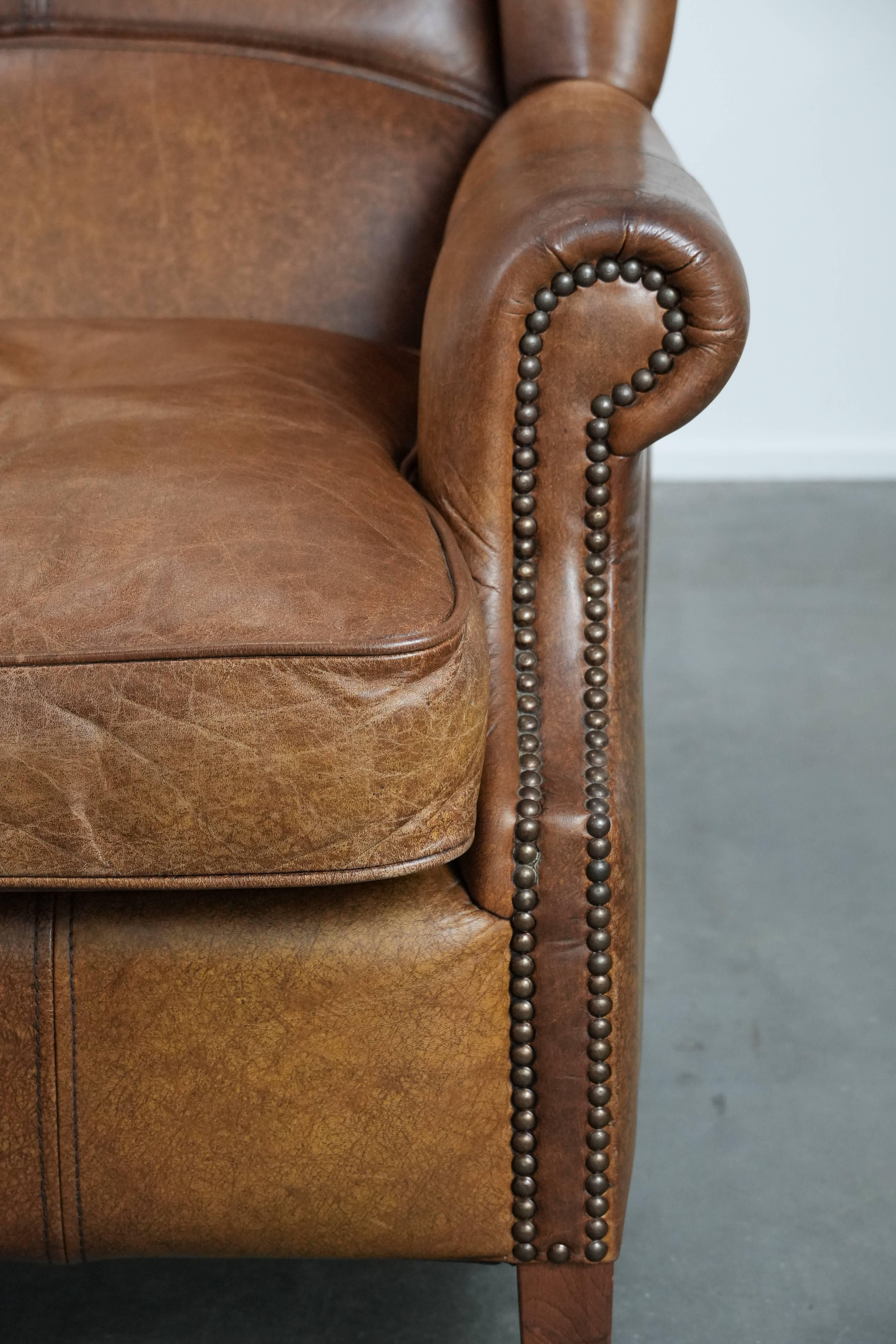 Cognac-coloured wingback armchair in English style made of cowhide ...