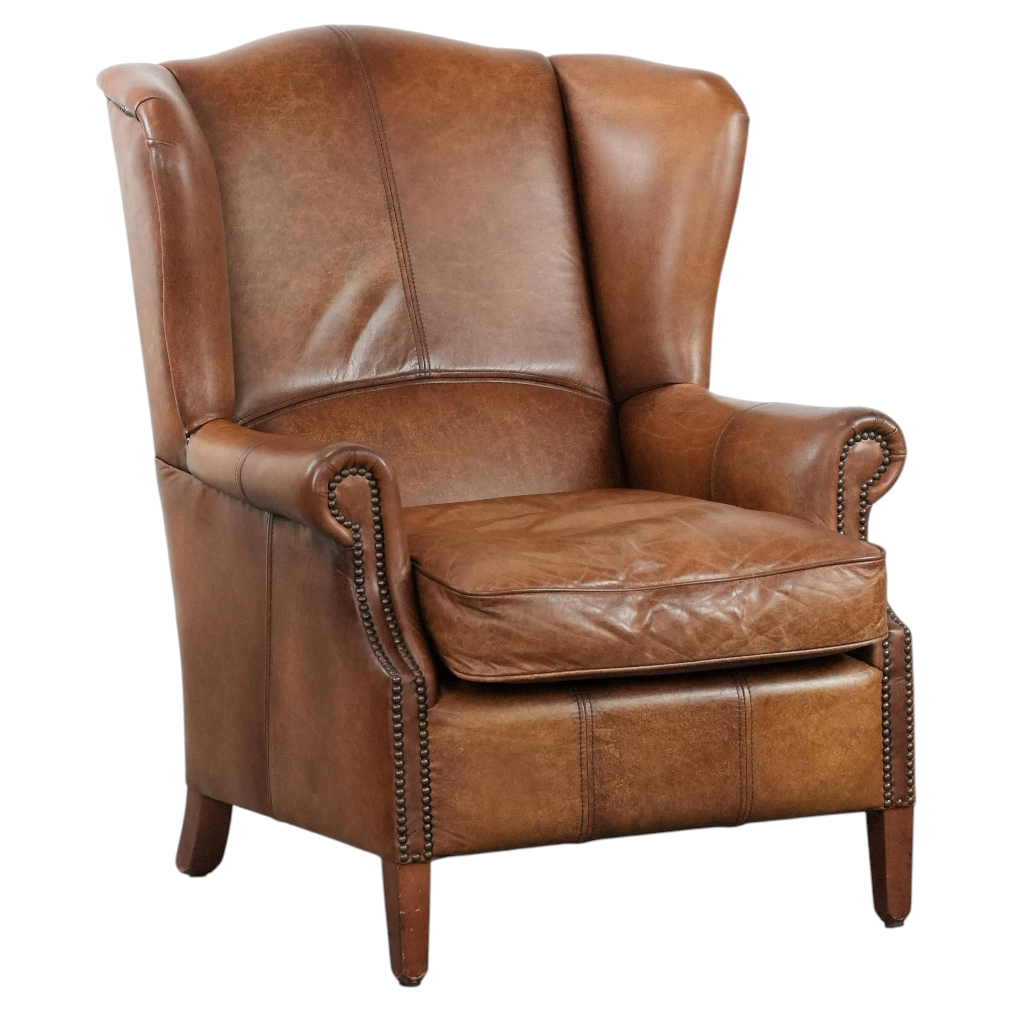 Cognac-coloured wingback armchair in English style made of cowhide leather For Sale