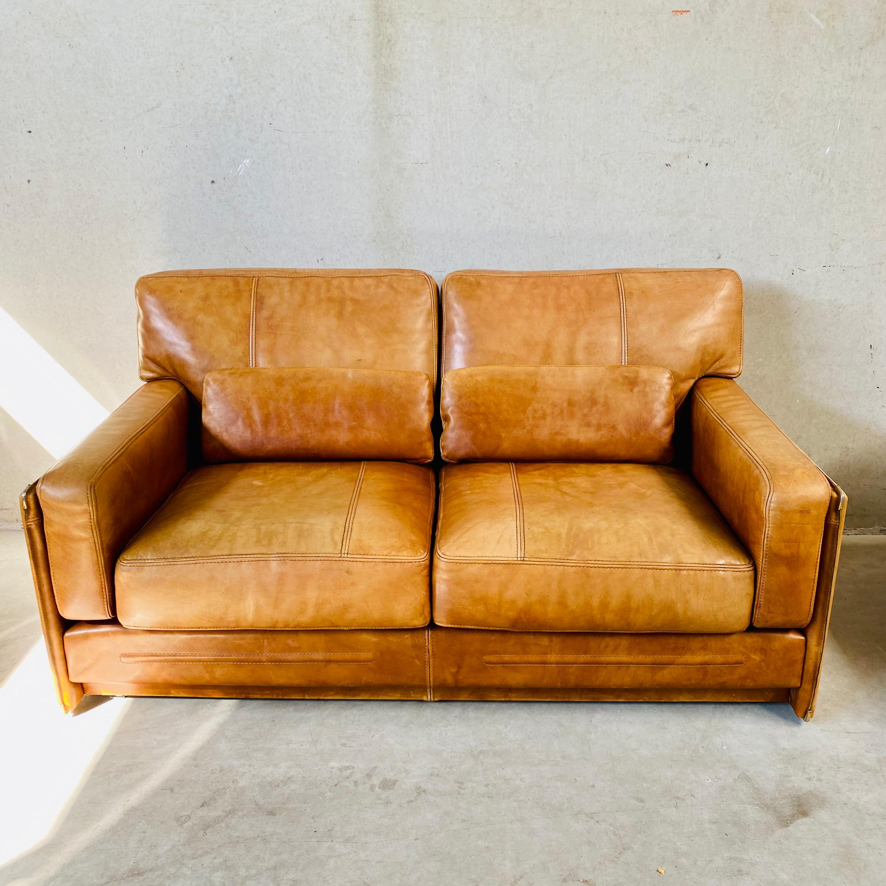 Introducing the exquisite cognac leather 2-seater sofa 1970 by Marco Milisich for Baxter Arcon - a true masterpiece of mid-century design. This stunning piece of furniture boasts a rich heritage that dates back to the 1970s, when Marco Milisich