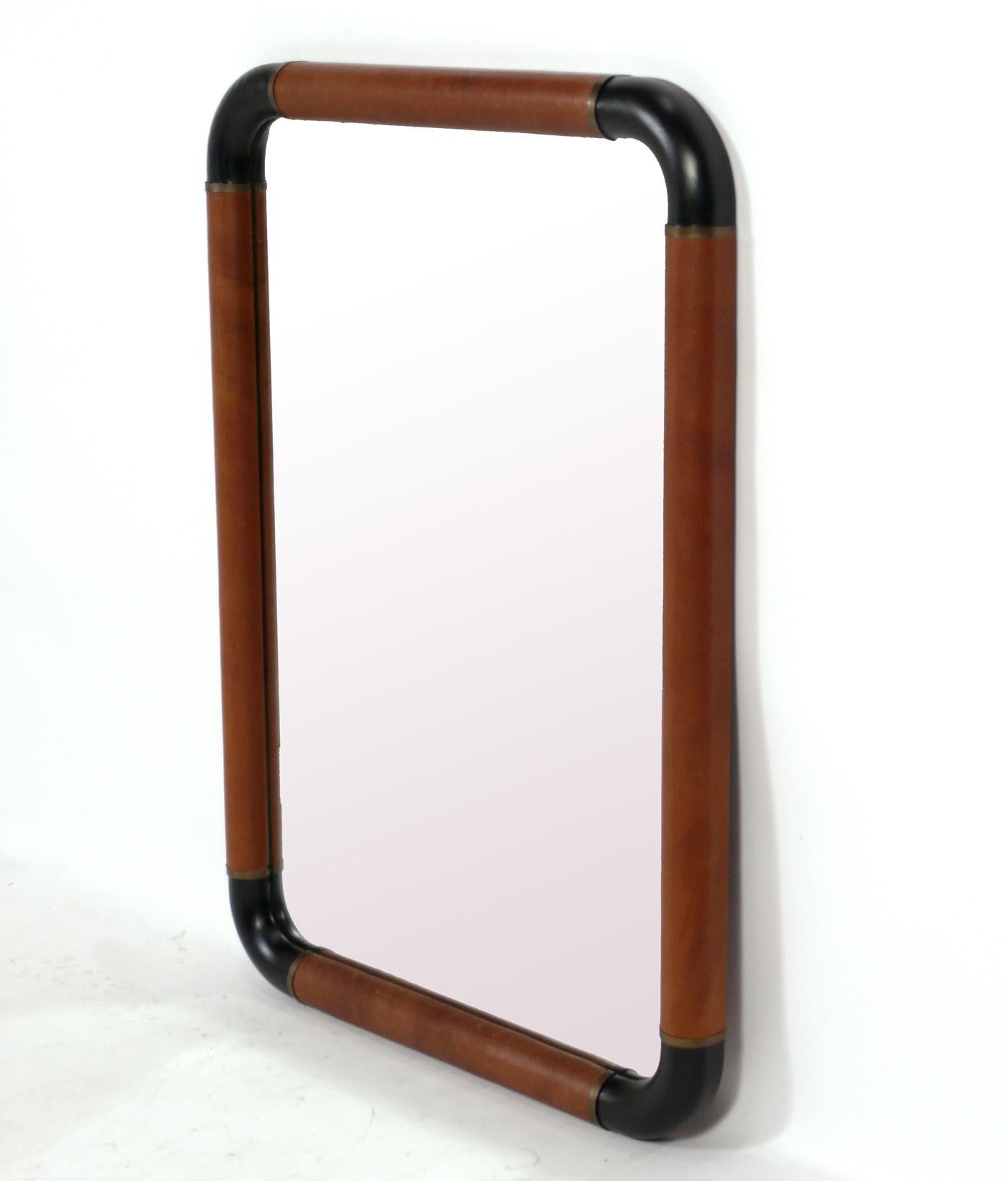 Cognac Leather and Black Oak Mirror with Brass Trim, in the manner of Jacques Adnet, France, circa 1960s. The black stained oak portions have recently been refinished. The cognac leather and brass elements retain their warm original patina. 