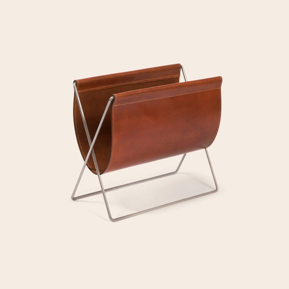 Cognac leather and steel Maggiz magazine rack by OxDenmarq
Dimensions: D 24 x W 47 x H 43 cm
Materials: Steel, Leather
Also Available: Different leather and frame colors available.

OX DENMARQ is a Danish design brand aspiring to make beautiful