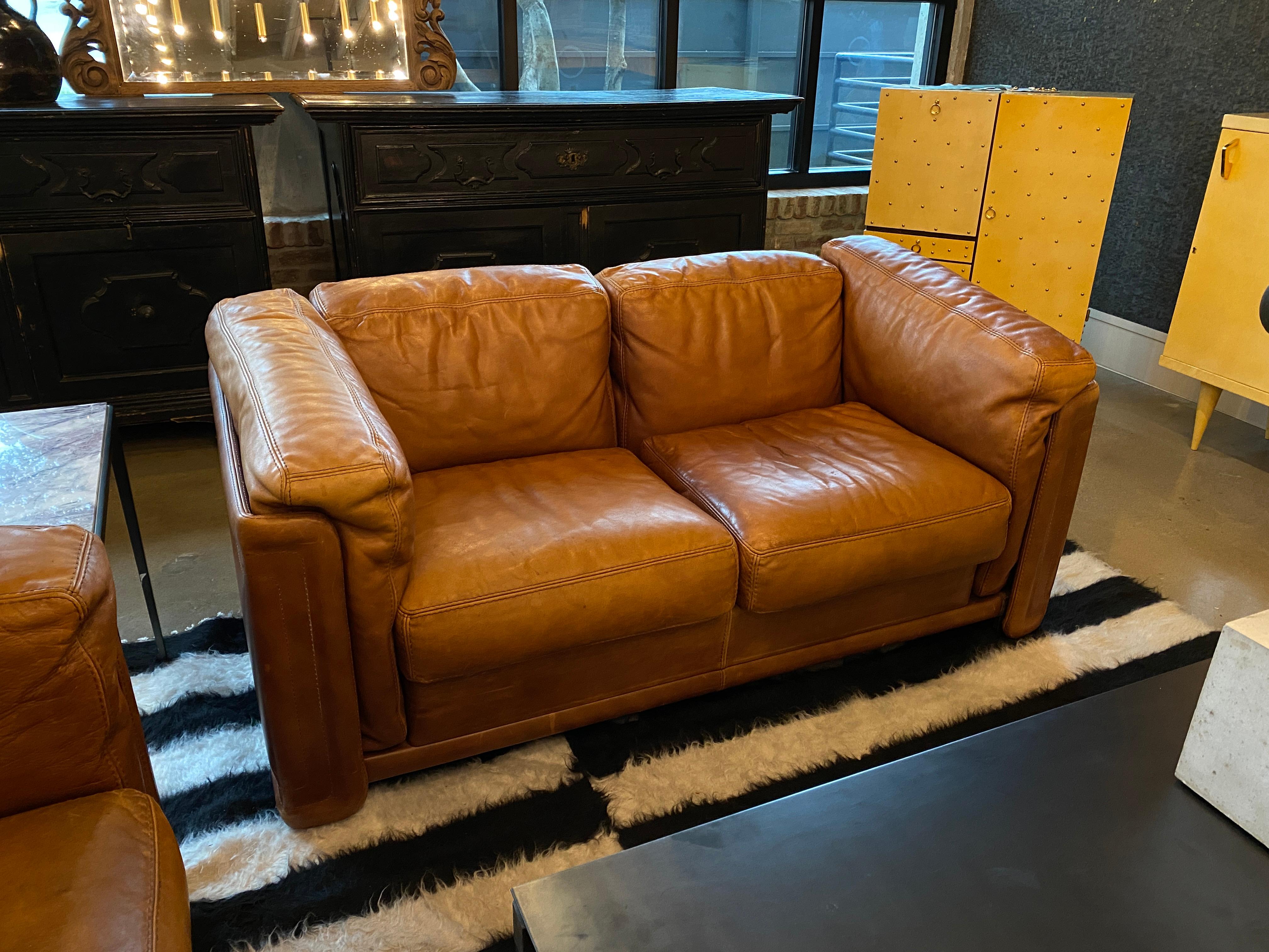 Large and comfortable vintage loveseat in cognac leather with great patina. Heavy wrapped leather frame shelters soft seat and back cushions, all with decorative top-stitching. Matching sofa (#LU1140218377992) and chair (#LU1140218377842) also