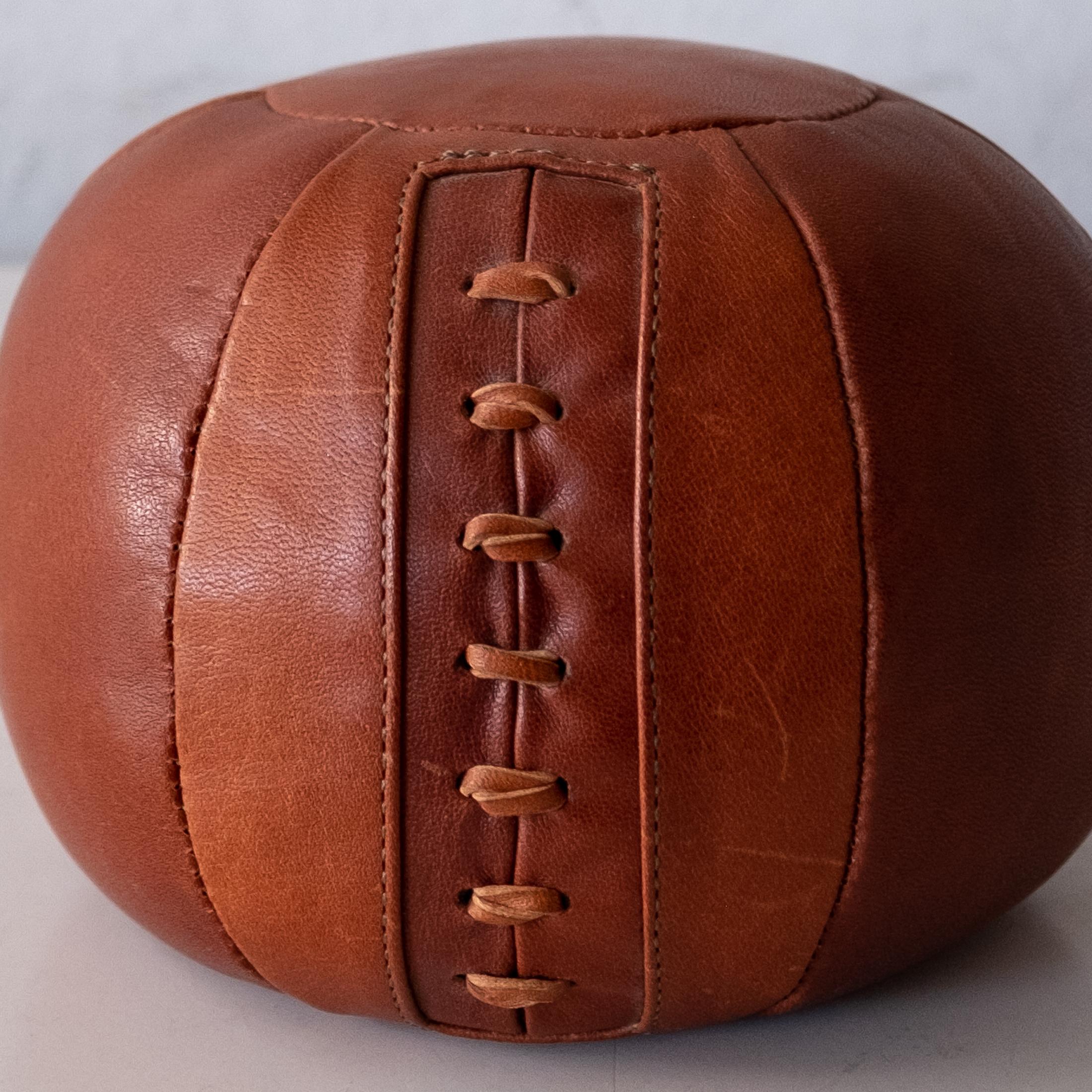 Cognac leather weighted medicine ball. Table top size to use as a decorative object or paperweight. Hand stitched high quality supple leather.