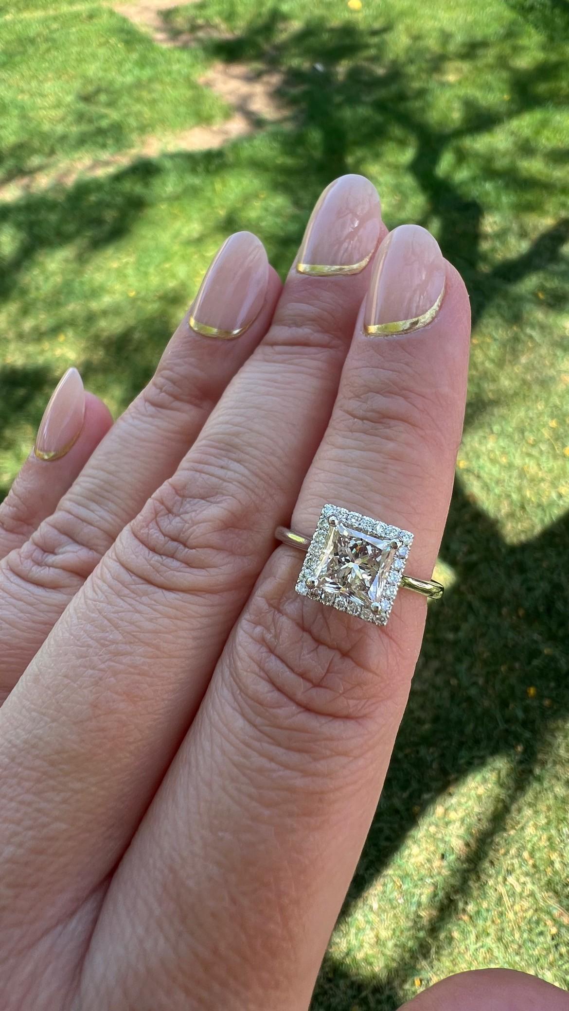 Questo squisito anello mette in mostra uno splendido diamante taglio princess cognac da 1,85 carati, famoso per la sua unica e calda tonalità. La magnifica pietra centrale è circondata da una delicata aureola di brillanti bianchi, che ne amplificano