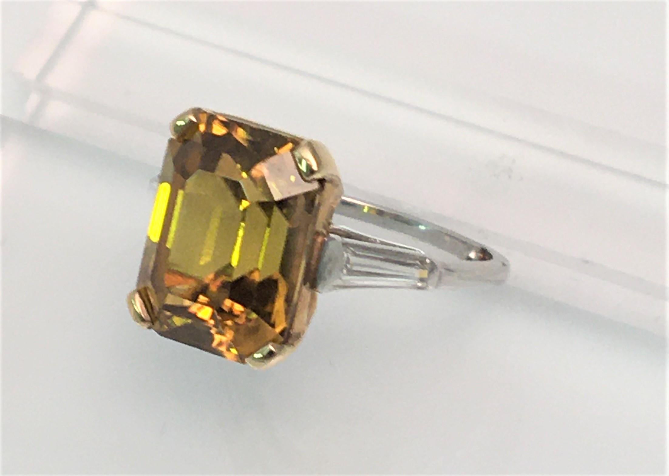 This beautiful cognac colored zircon is said to heal headaches and ground your spirit.*  

Approximately 13mm X 10mm X 6.5mm emerald cut cognac color zircon
One long, tapered baguette diamond set in platinum on each side of ring
Approximately .32