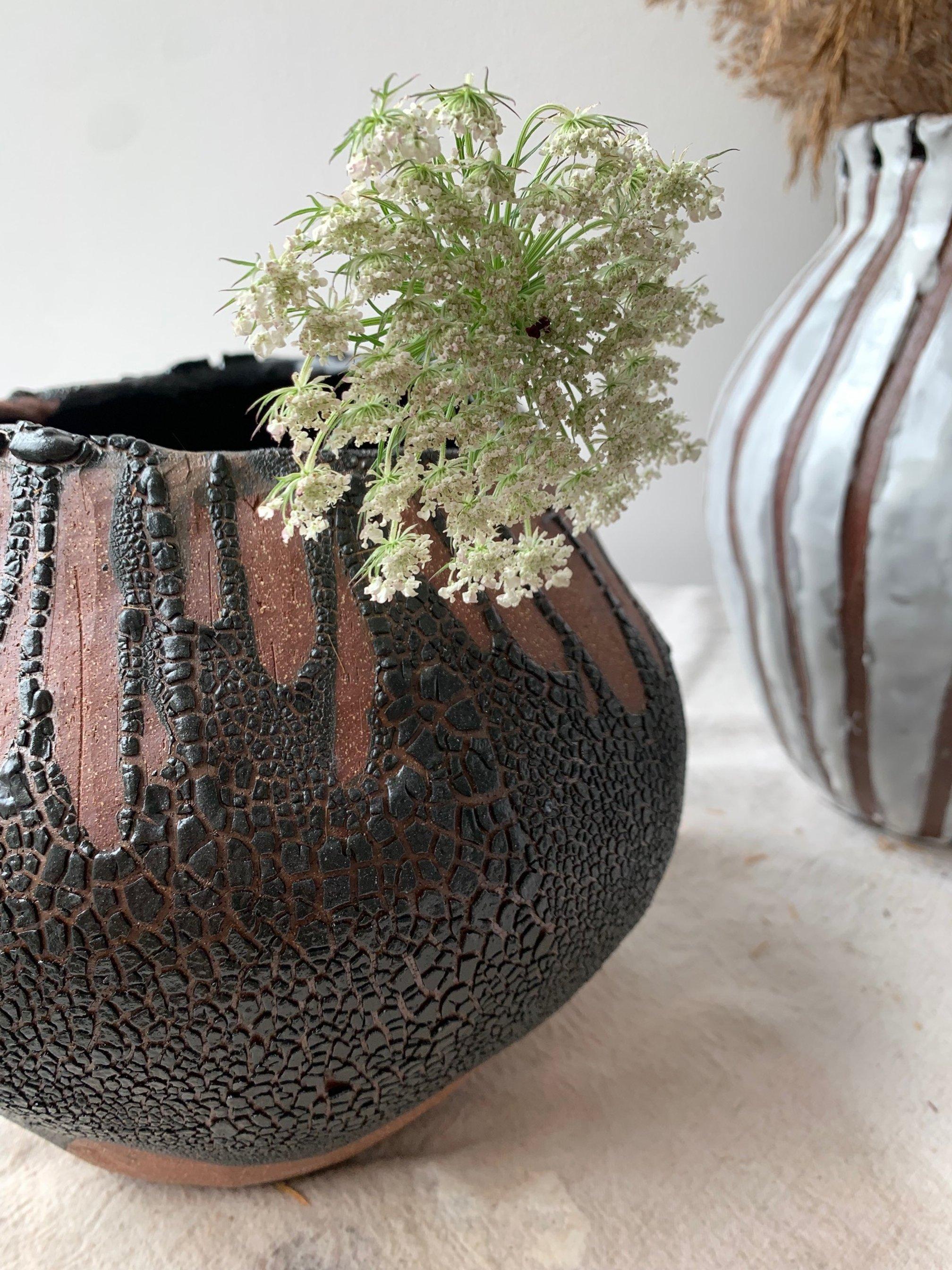Organic modern coil-built vase paddled and carved into a perfectly asymmetrical shape. Intuitively formed vase features layers of crawling black glaze on the exterior, and a gloss black interior.


Approximately 8” tall and 10” diameter, with