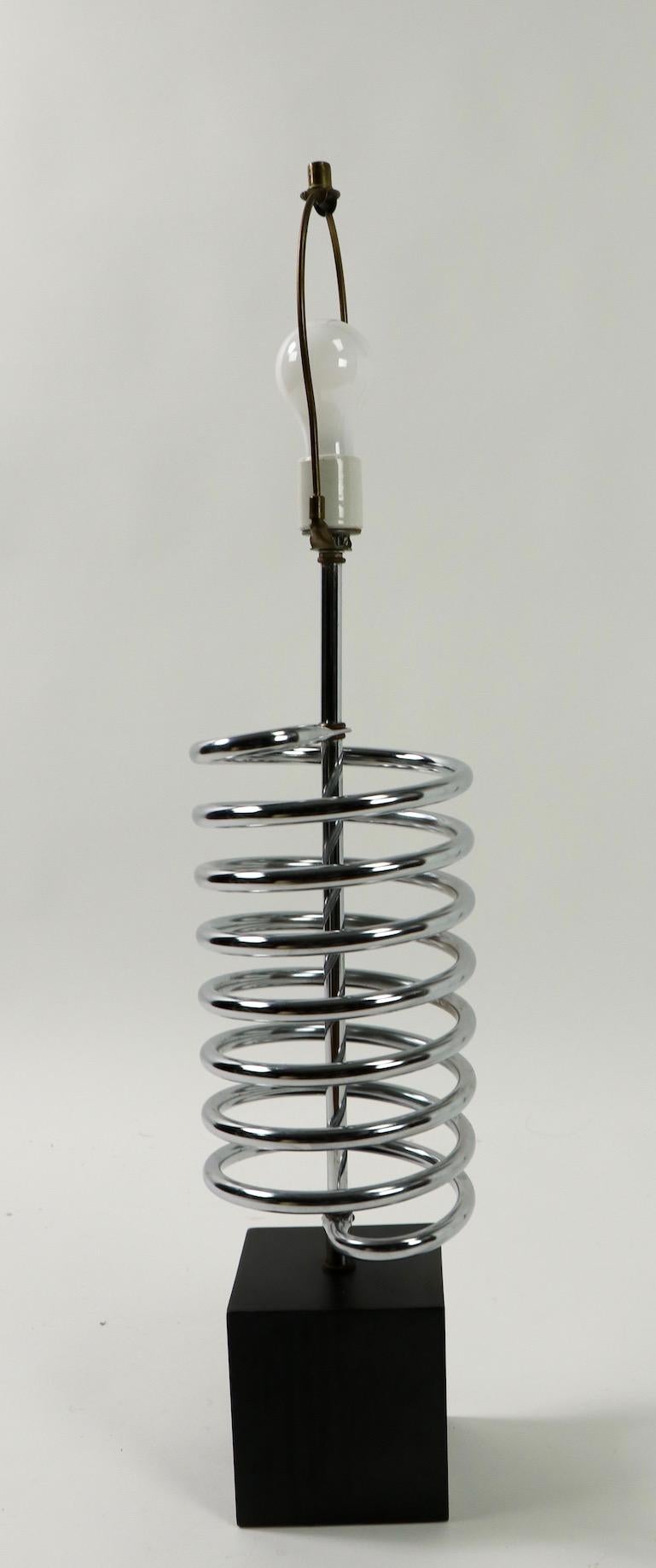 Chrome coil spring mounted on black base (Base 5 W x 5 D x 5.5 H inch). Lamp total H 33 inch x H to top of coil 18.5 inches. Clean, working condition, accepts standard size screw in bulb. Manufactured by Sonneman Lighting Company circa 1960s-1970s.