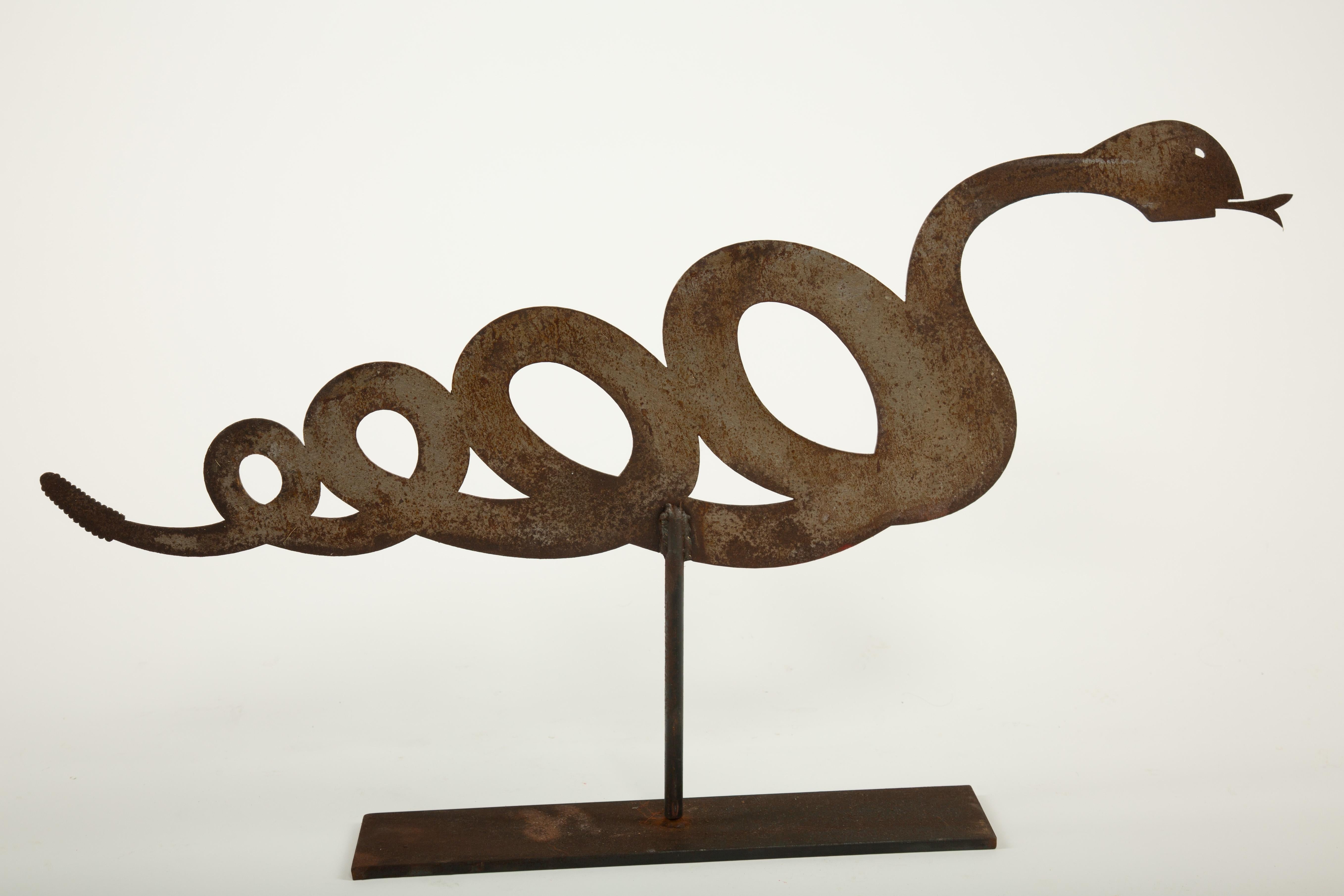 Snake Weathervane on Stand
A late 19th to early 20th century cut-sheet iron weathervane in the whimsical form of a coiled snake, its body rendered in a continuous looping silhouette with a pointed tongue extending from the head. Retaining a rich,