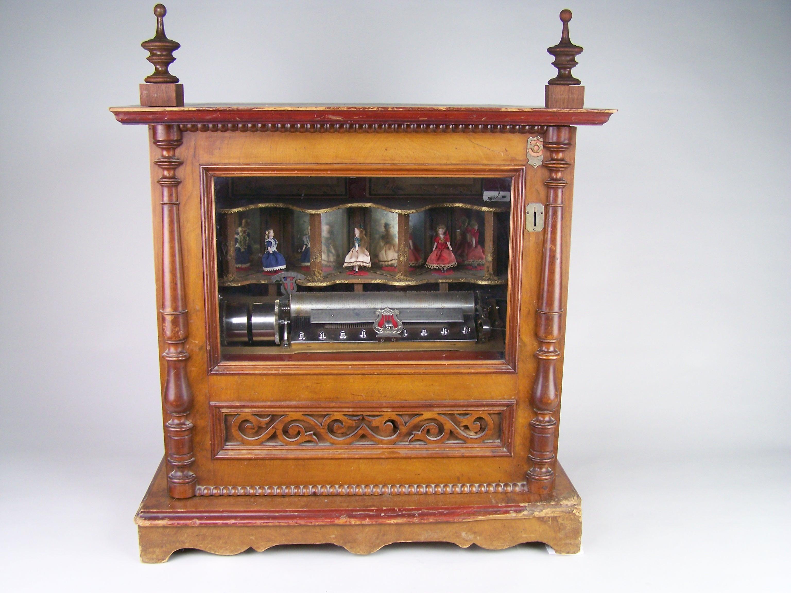 Large station music box with 3 dancing dolls.

This music box was probably made by Ullman at the end of the 19th century in Switzerland. This type of box was produced to be placed in stations, where passengers could listen to a melody and watch the
