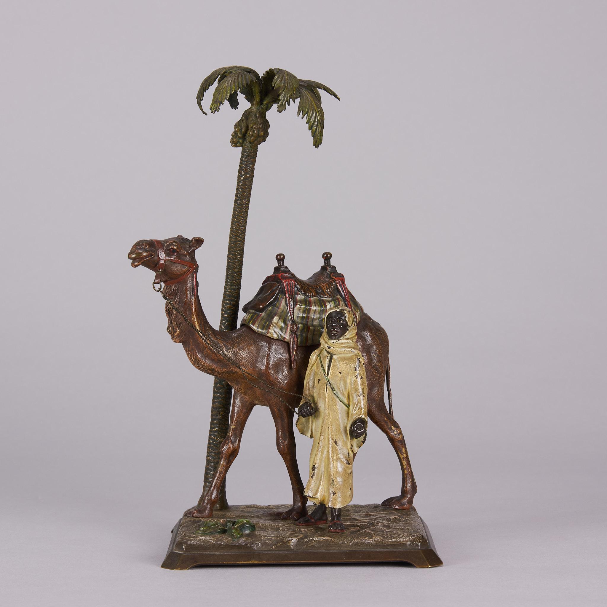 Eine auffällige österreichische Bronzegruppe aus dem frühen 20. Jahrhundert mit einem Beduinenmann, der neben seinem Kamel an einer Palme steht, auf einem naturalistischen, erhöhten Sockel. Der Sattel des Kamels lässt sich öffnen und gibt den Blick