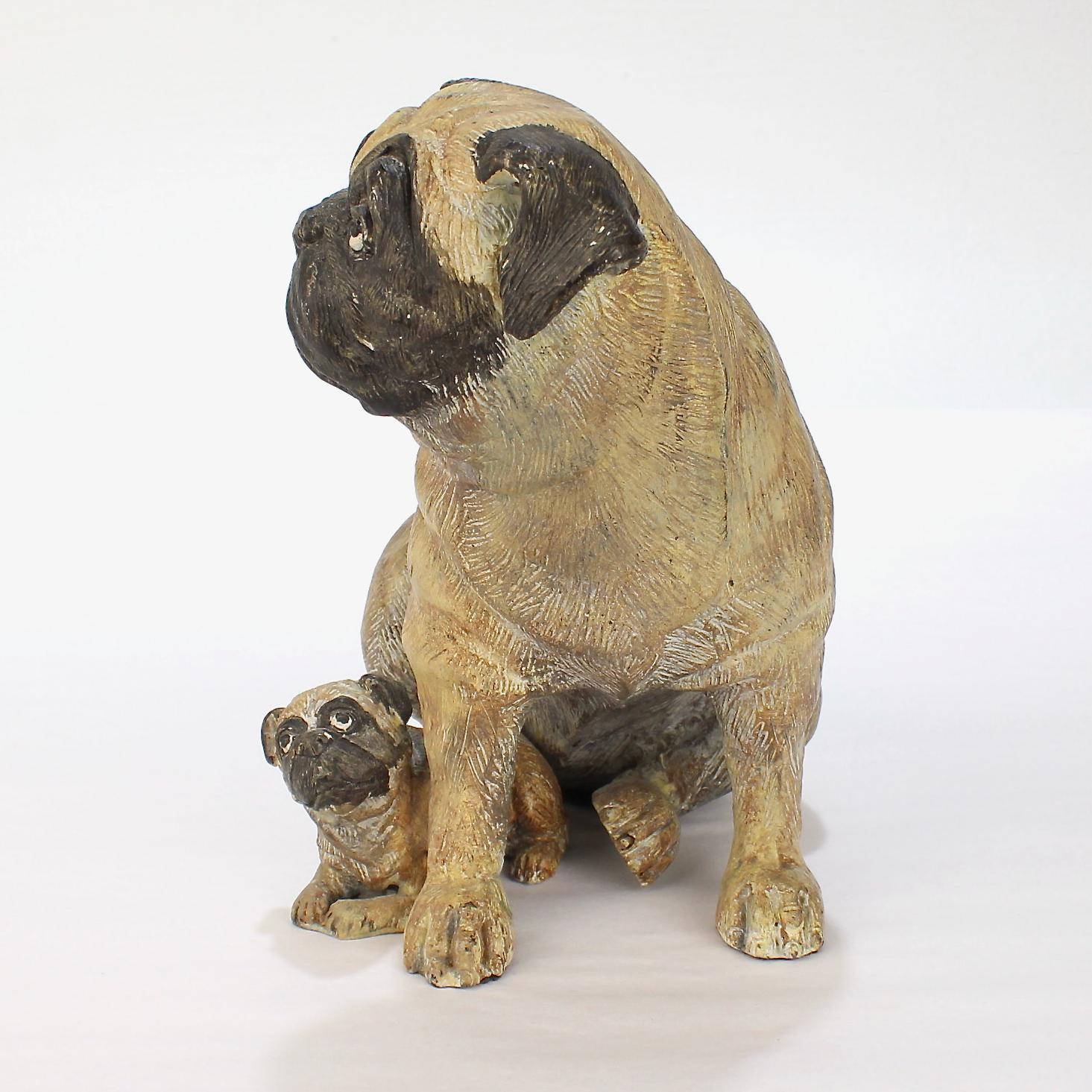 A very fine cold-painted pug mother and puppy bronze sculpture. 

With a small puppy nestled at its mother's feet depicted in the manner of the 18th century Meissen porcelains modeled by Johann Joachim Kändler.

From the collection of the