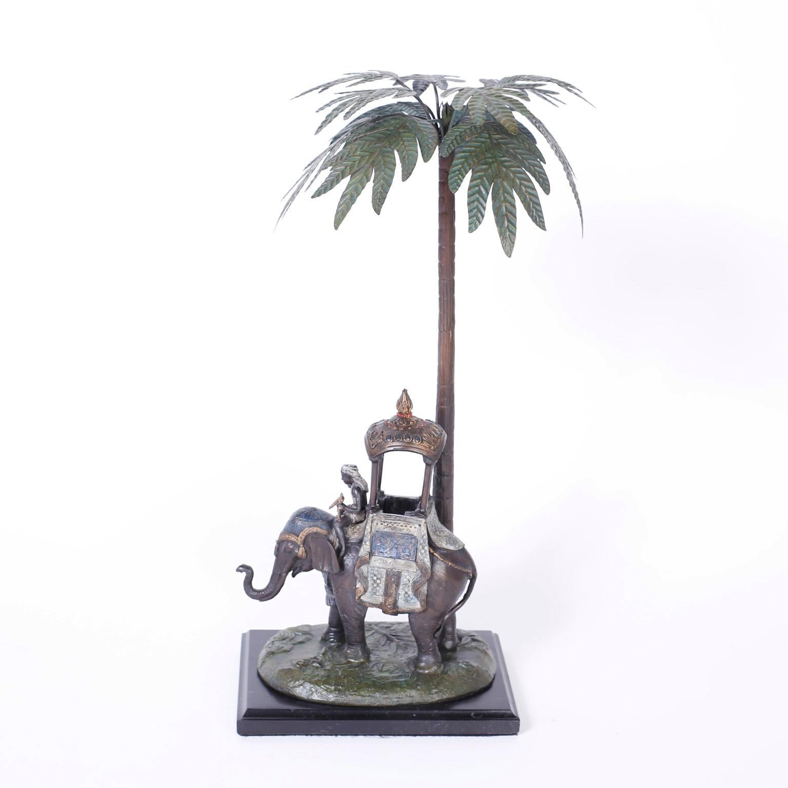 Transporting cold-painted Austrian metal elephant with a fanciful howdah and driver on a patch of terra firma under a Palm Tree with tole leaves.