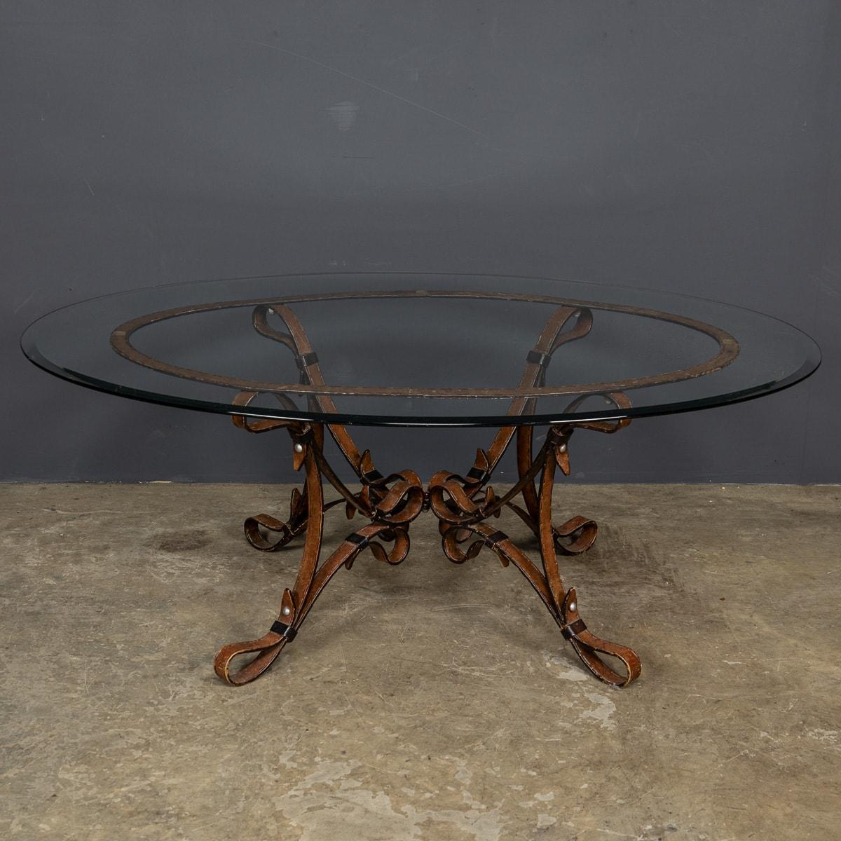 A superb late-20th Century coffee table featuring cold painted wrought iron straps meticulously crafted with intricate details. The straps elegantly converge, forming a sturdy base for an oval, beveled glass top. This cleverly designed piece boasts