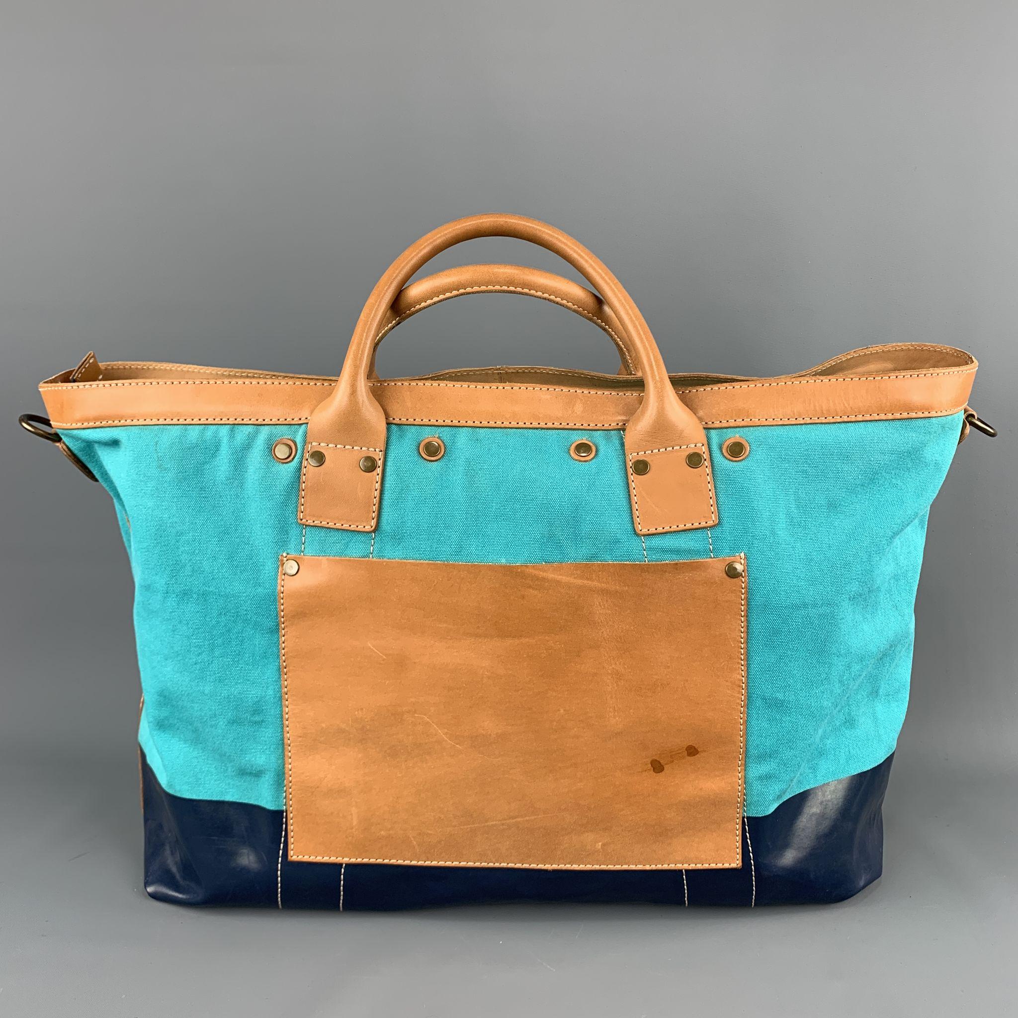 COLE HAAN Tote Bag comes in aqua and navy tones in two tones of a canvas material, rectangular, with a leather trim, gold tone metal zipper and hardware, a leather patch pocket outside and inner pockets. Minor wear.

Very Good Pre-Owned