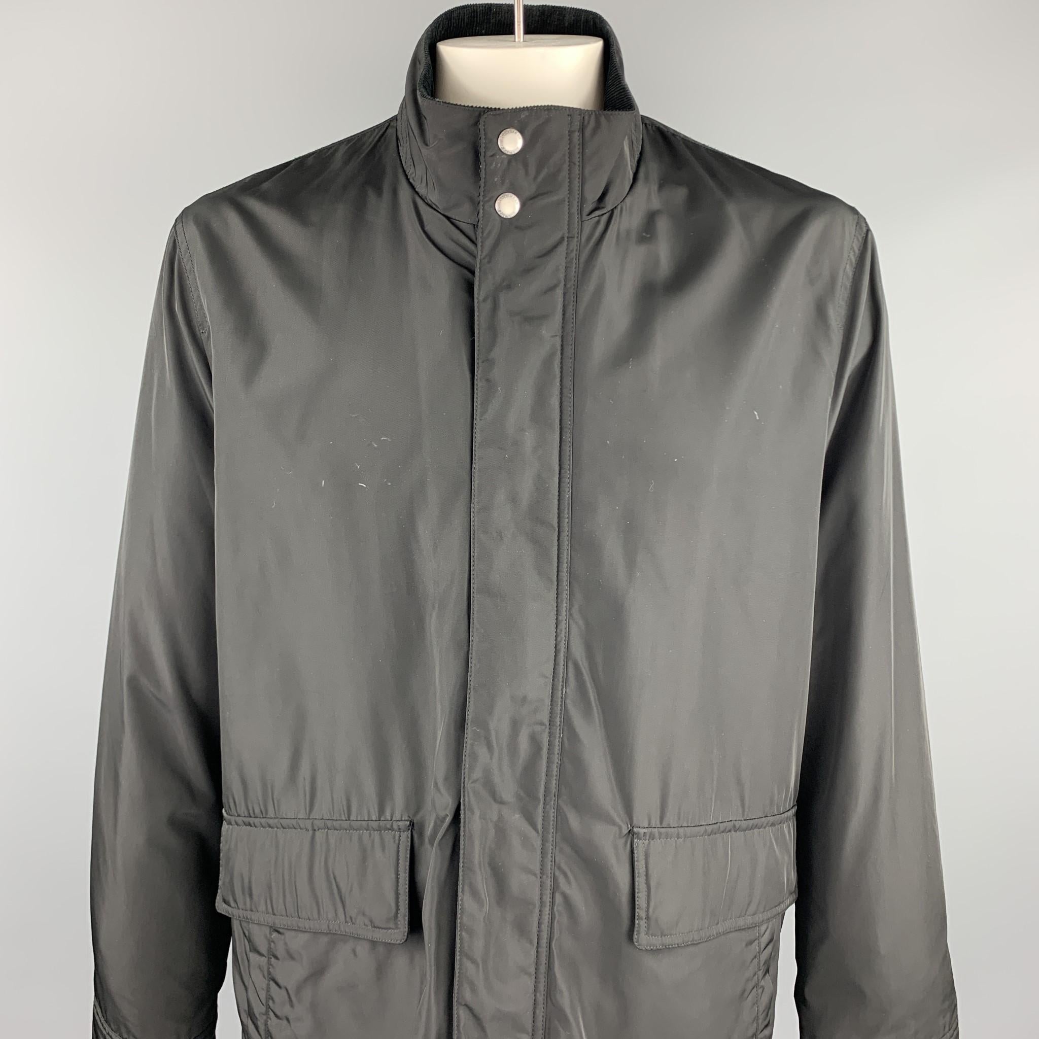 COLE HAAN jacket comes in a black polyester featuring a high collar, corduroy trim, patch pockets, and a zip & snap button closure. Minor marks. As-Is.

Good Pre-Owned Condition.
Marked: L/G

Measurements:

Shoulder: 19 in. 
Chest: 50 in.
Sleeve: 27