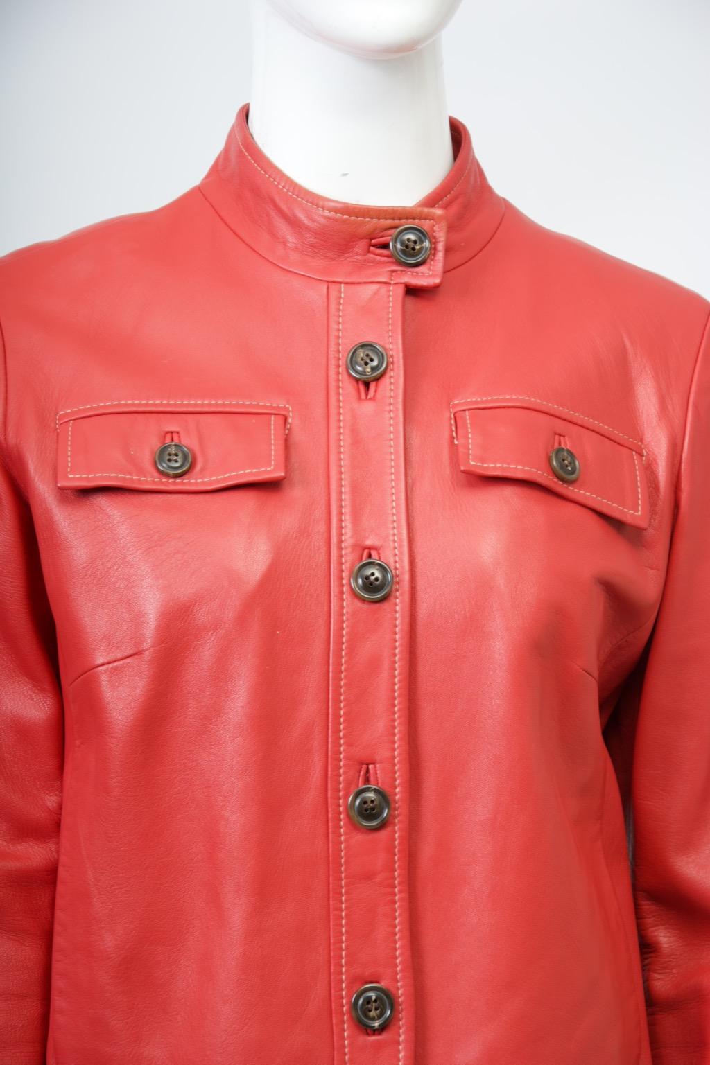 Chaqueta de piel roja vintage Cole Haan de estilo cropped y corte recto. 
La chaqueta presenta cuello falso con bandas, dobladillo, tapeta delantera y puños, así como dos bolsillos en el pecho con solapa, todo ello perfilado con pespuntes superiores