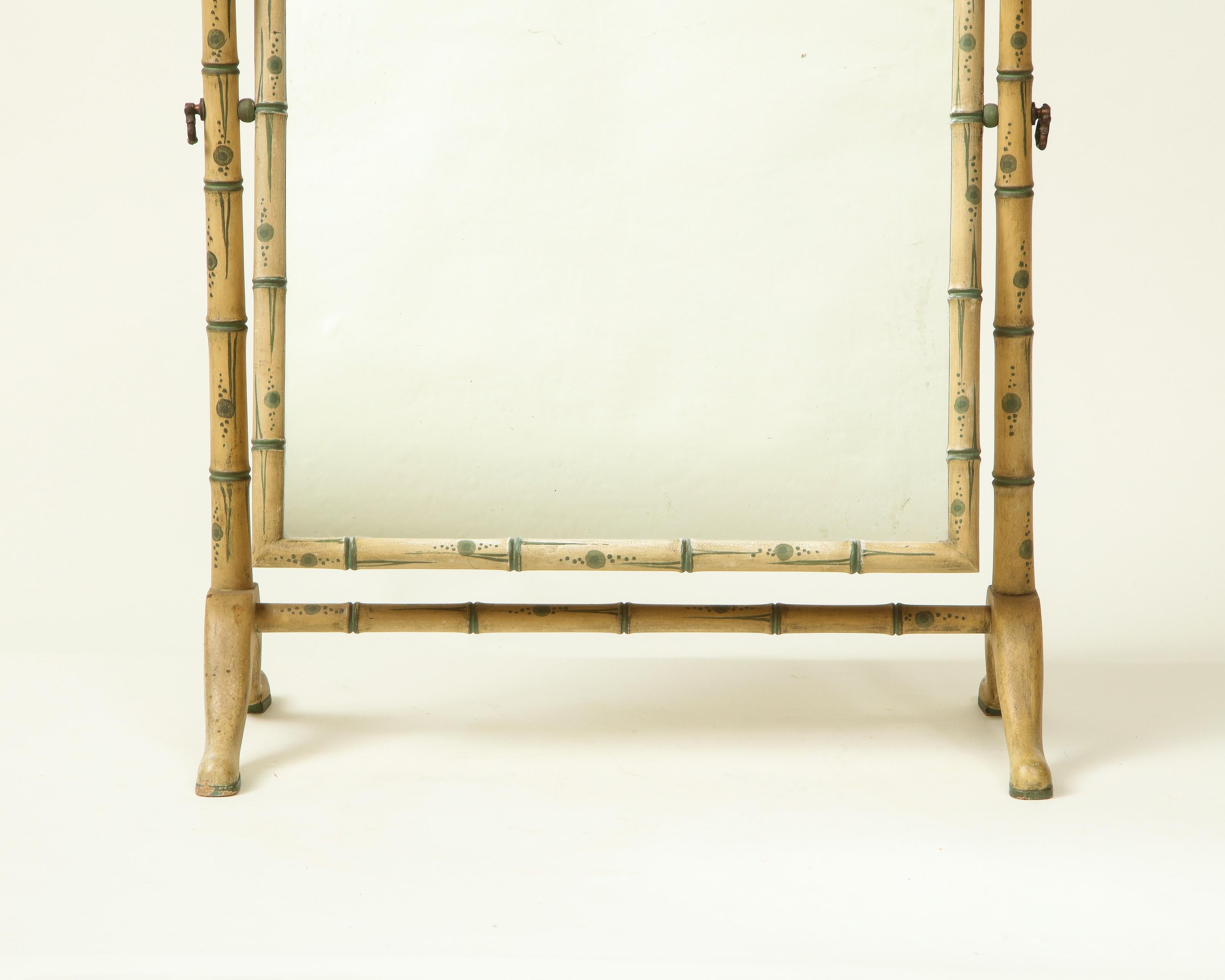The arched rotating mirror plate within a conforming ivory painted wood surround with blue bamboo detailing, supported by two side uprights joined by a stretcher.

Provenance: From the Collection of Mario Buatta, New York, NY.