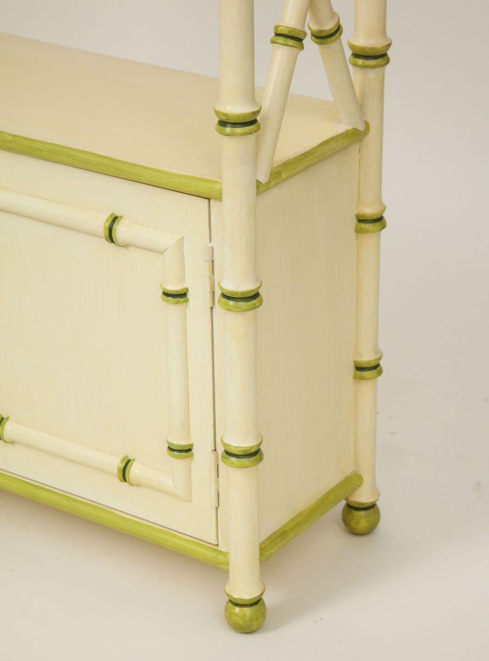 With a shelf over paneled cabinet doors, articulated throughout with stylized bamboo ridges; painted in cream, this one with green detailing. (Other with blue detailing also available)
