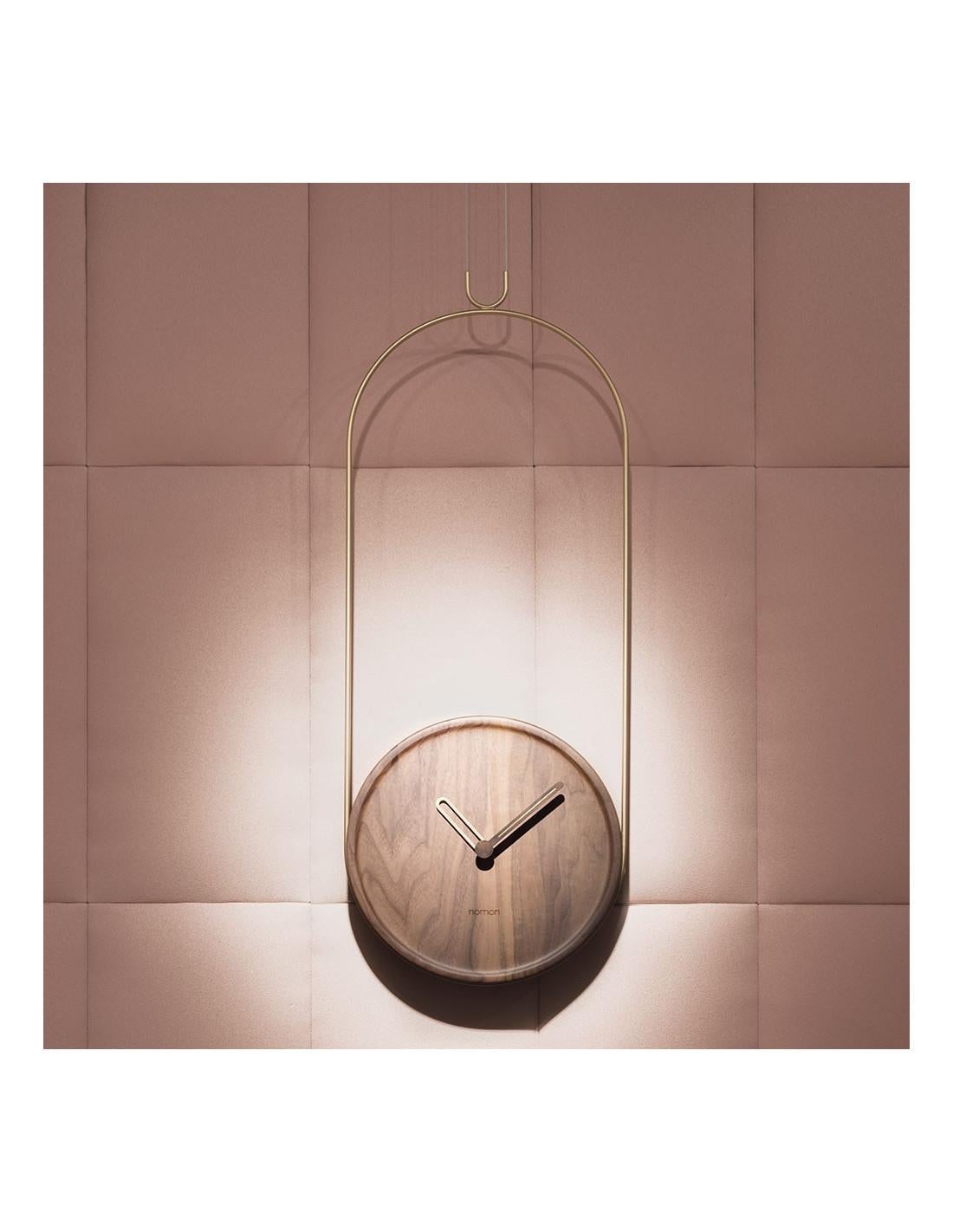 The Colgante Walnut is a sophisticated wall clock that is suspended from a curved metal rod finished in polished or black brass.
Colgante Walnut Wall Clock : The Case is made of Walnut wood , Needles made of Walnut wood with polished brass or black