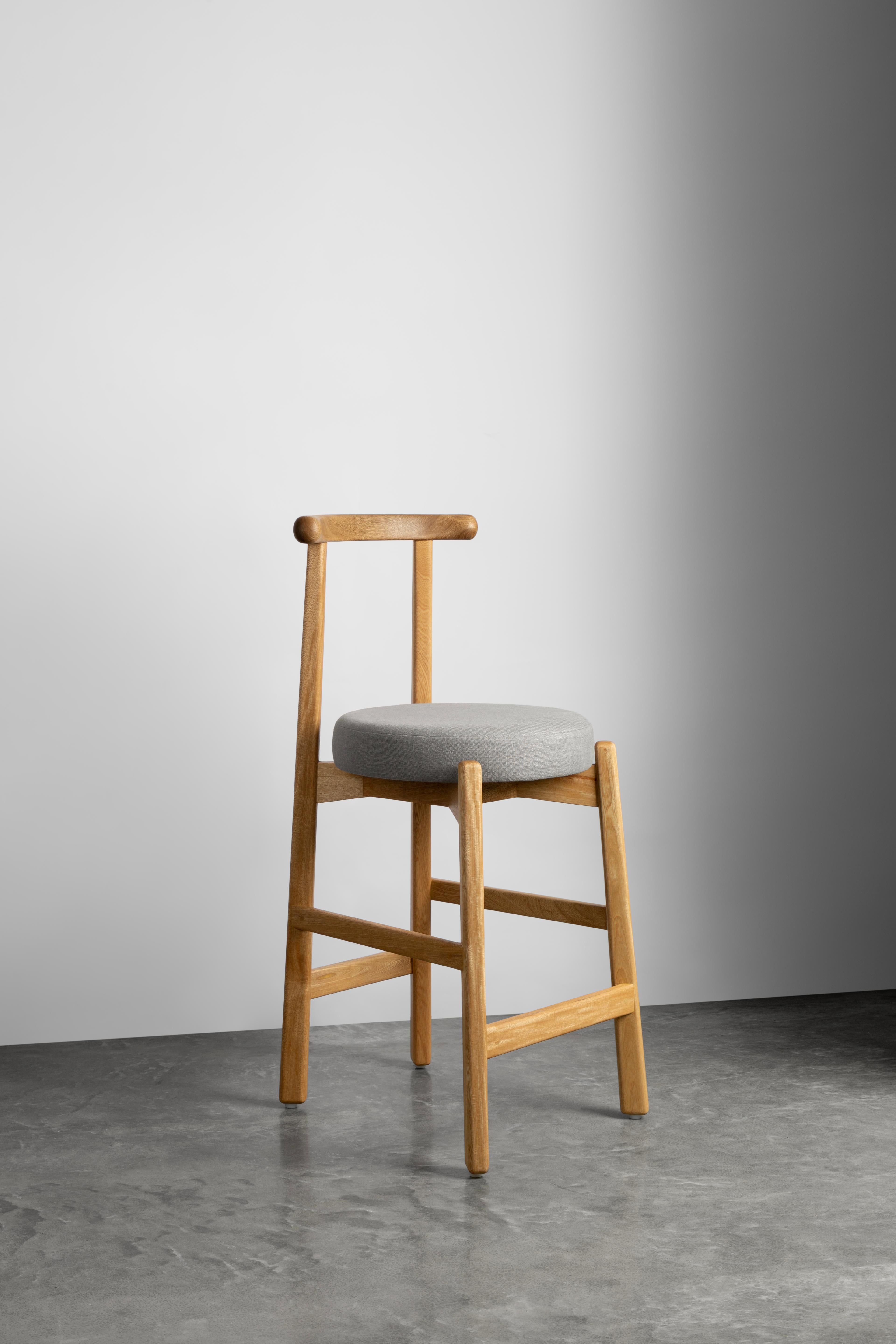 This stool comes from one of our best-selling pieces: the Colima chair. Available in two
different versions, this stool is ideal for the kitchen bar or a perch table. Made of solid wood with fabric upholstered seat, you can have many different