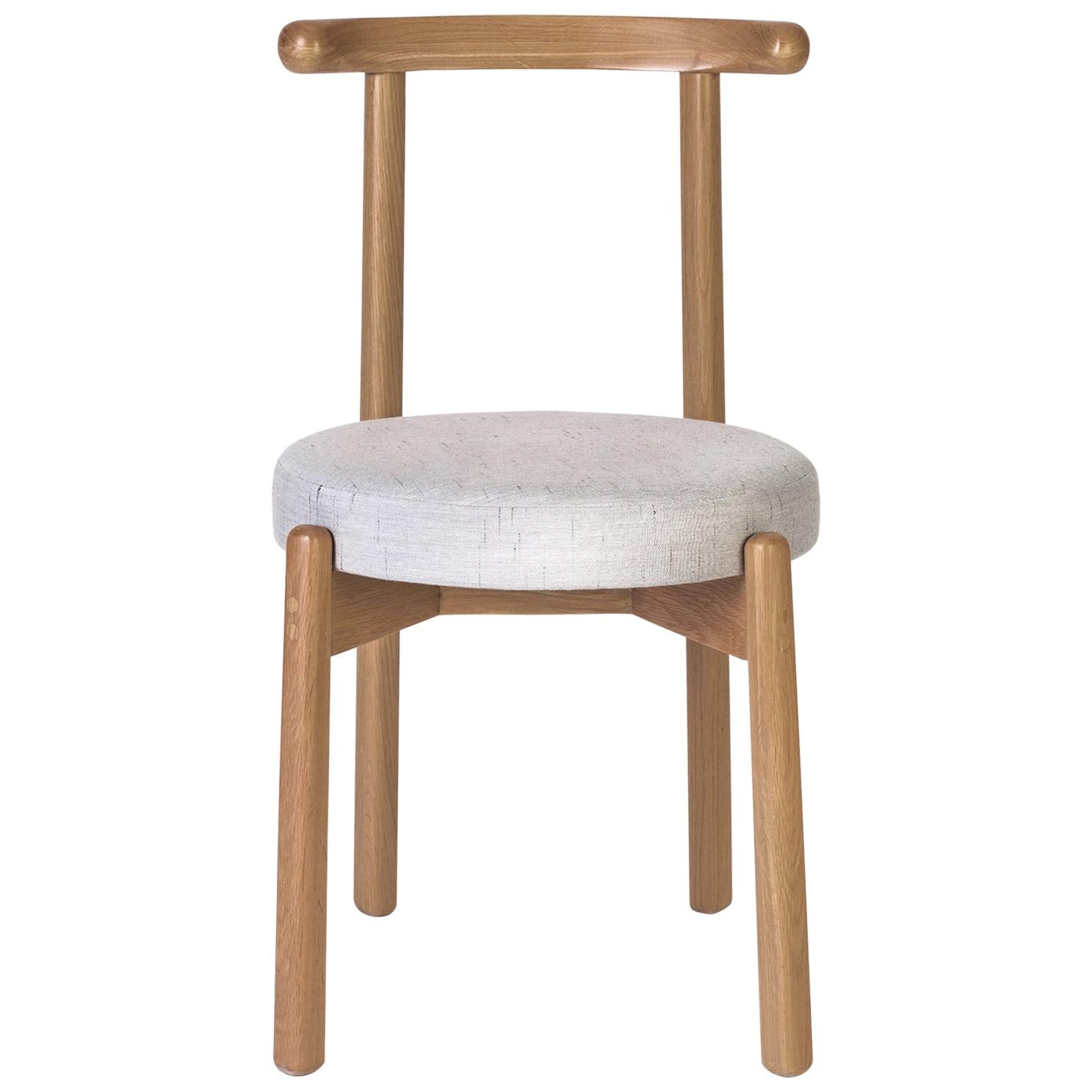 La simplicité de ce design fait de cette chaise une pièce polyvalente qui peut s'adapter à plusieurs types de tables à manger et d'espaces. La structure est en bois de chêne massif. Le revêtement des coussins peut être modifié sur demande selon les