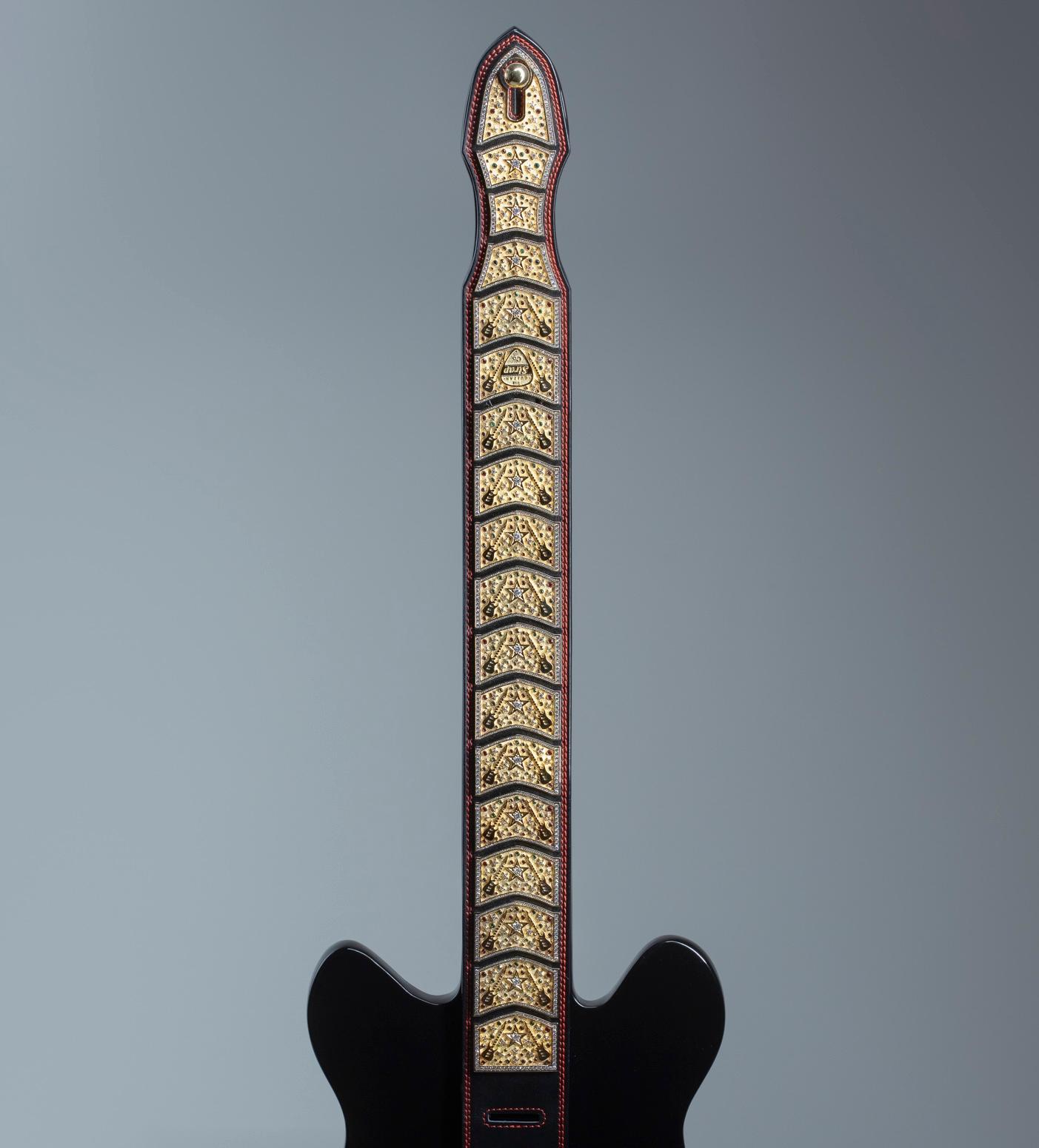 "Showstopper": cinturino per chitarra unico in oro 18 carati e diamanti di Colin Burn

Media: Pelle, oro giallo 18 carati, diamanti, rubini, zaffiri e smeraldi  
ATT: solo la tracolla - la chitarra non è inclusa.

NOTA: il tempo di preparazione può