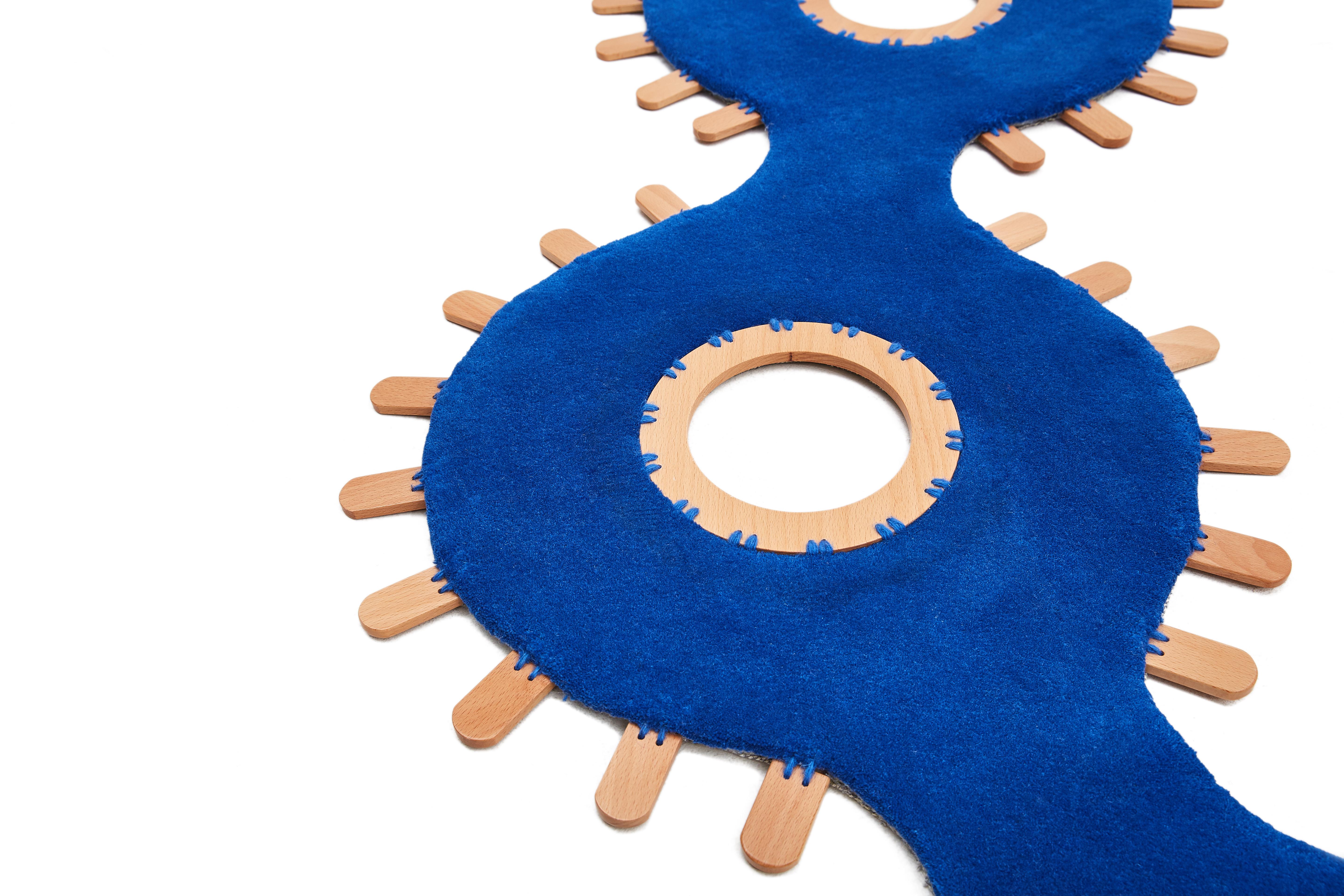 Der Collana-Teppich ist ein Hybrid aus Wolle und Holz, der eine Spannung zwischen verschiedenen Materialien und DNA erzeugt. Inspiriert von Halsketten und Armbändern, verlässt das Ornament den Körper, um das Haus zu schmücken, in einem breiteren und