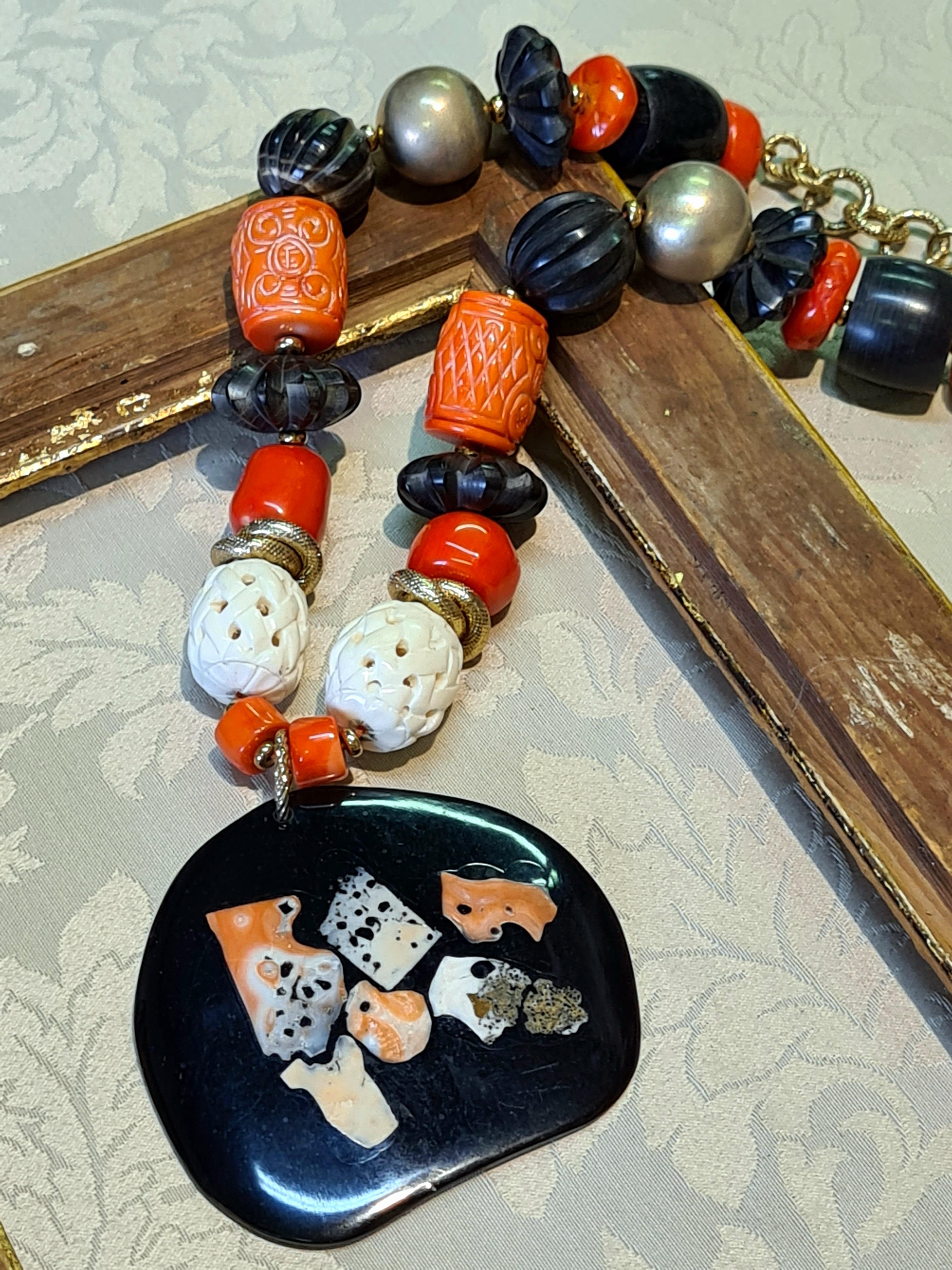 Necklace composed of large Horn Plate with inlaid natural Mediterranean Coral. Finely worked Horn elements, smooth Bamboo Coral and orange inlaid Bamboo Coral complete the necklace along with two large 925 Sterling Silver spheres plated with 24K