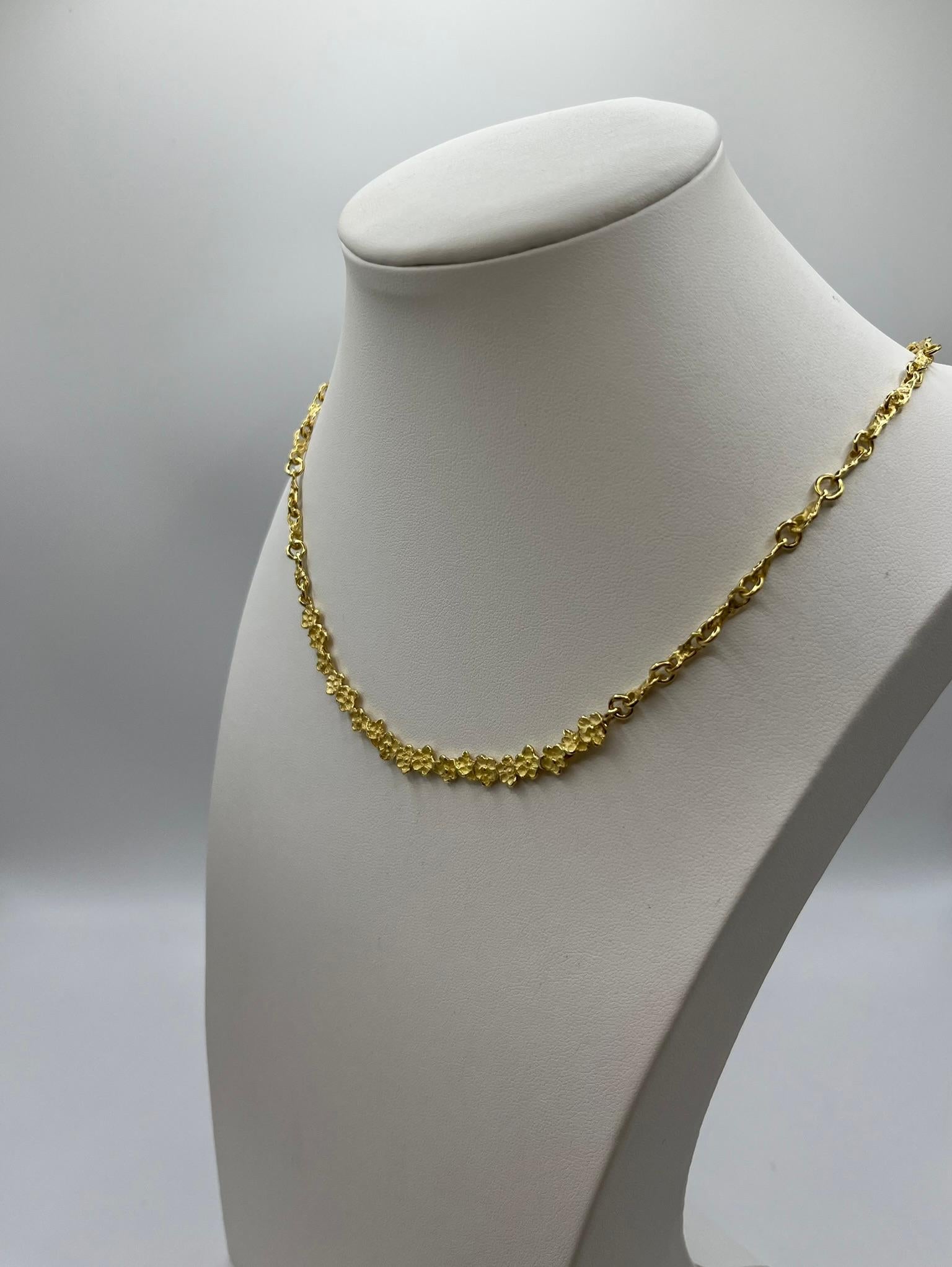 Elégant collier ras de cou entièrement r�éalisé en or jaune 18 carats. 750/00. Il a été conçu et fabriqué à la main en Italie et présente un motif spécial de fleurs en relief dans la bande centrale, le reste du collier étant constitué d'une chaîne.