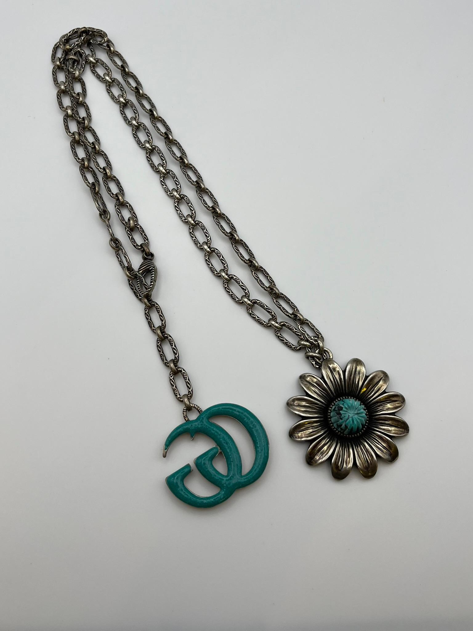 Gucci-Halskette aus der Gg Mormont-Kollektion. Silberne Halskette mit antikem Finish auf den Gliedern. Der bezaubernde Blumenanhänger mit türkisfarbener Emaille ist ein wiederkehrendes Motiv in der Kollektion und ist auf der Rückseite wunderschön