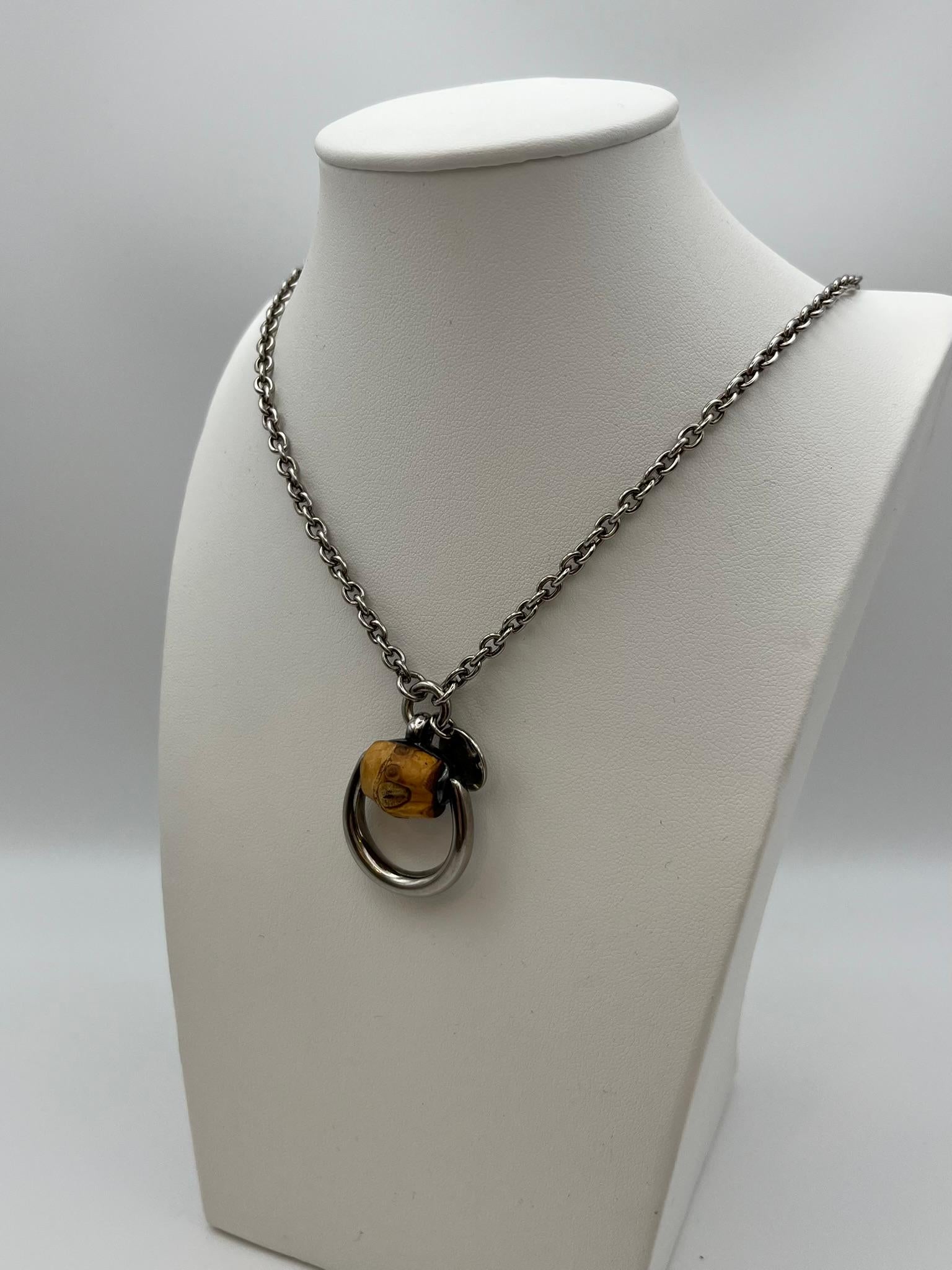 Collier Gucci de la collection Horsebit avec cylindre en bambou naturel. Elle se caractérise par une chaîne à maillons ovales en argent sterling 925 avec un fermoir à mousqueton ; deux maillons ovales plus grands permettent de régler la longueur. La