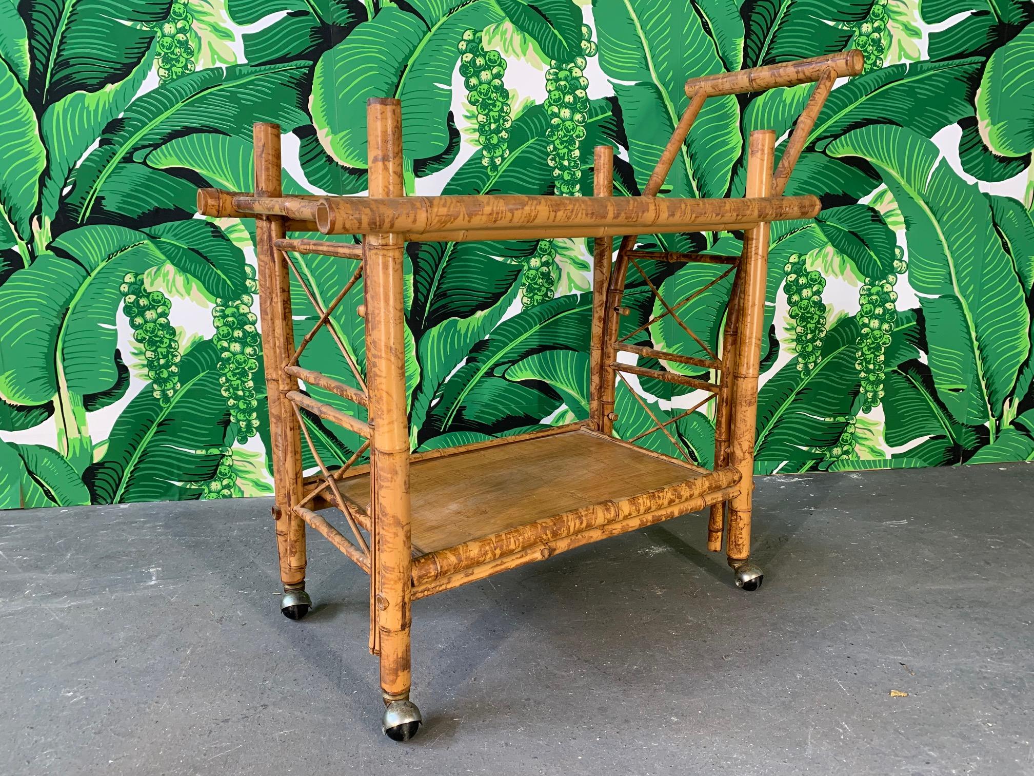 Vintage bar or tea cart in tiger bamboo features a collapsible design allowing for simple deconstruction for easy storage or transport. All pieces assemble with attached bamboo pins. Brass castors for smooth rolling into any room. Very good