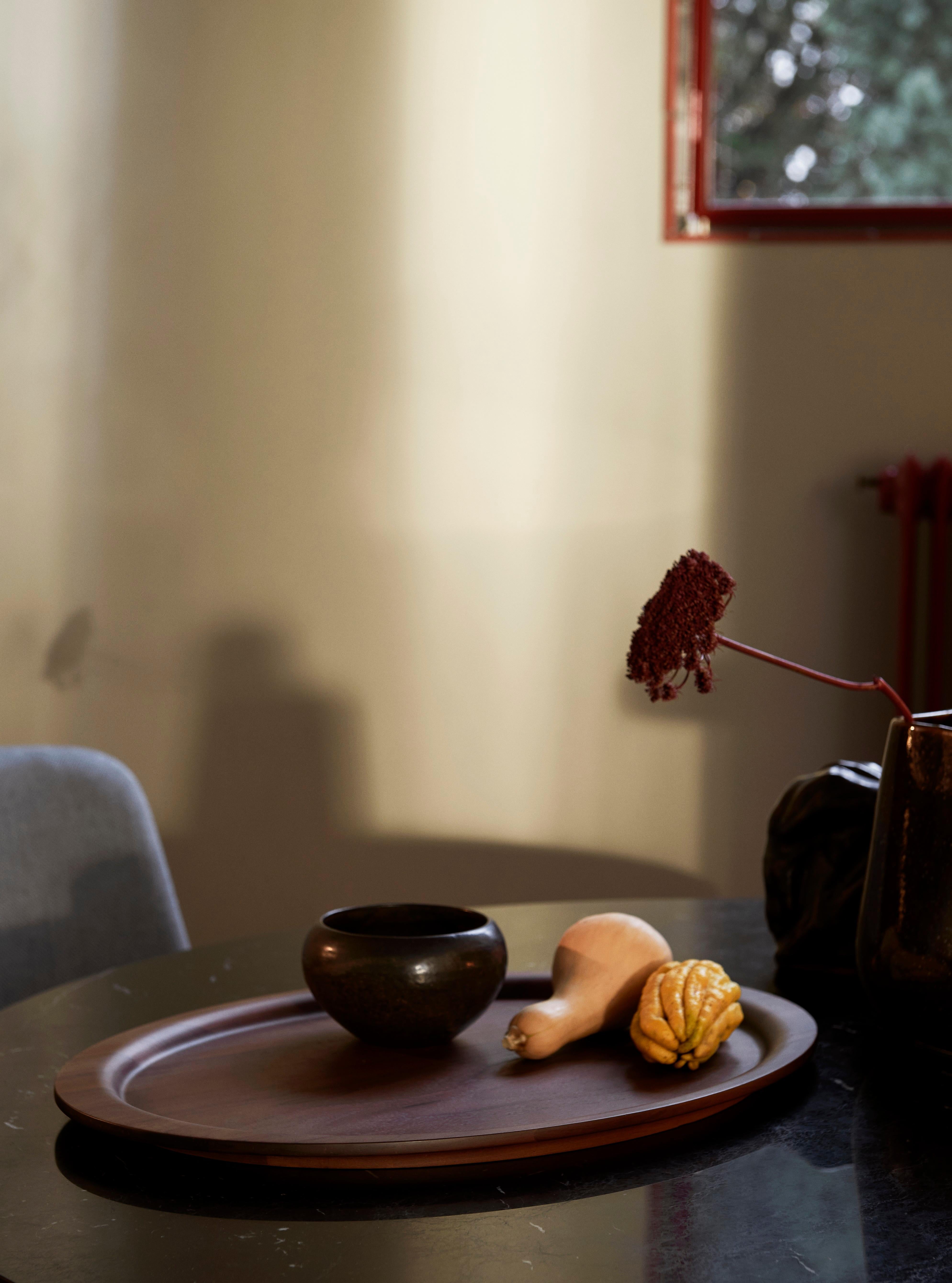 Carved from solid oak or walnut, this gently curved tray boasts a fluid shape while displaying the material's natural veining throughout the wood's surface. 
It sits within Collect, a curated line of beautifully crafted soft furnishings and home