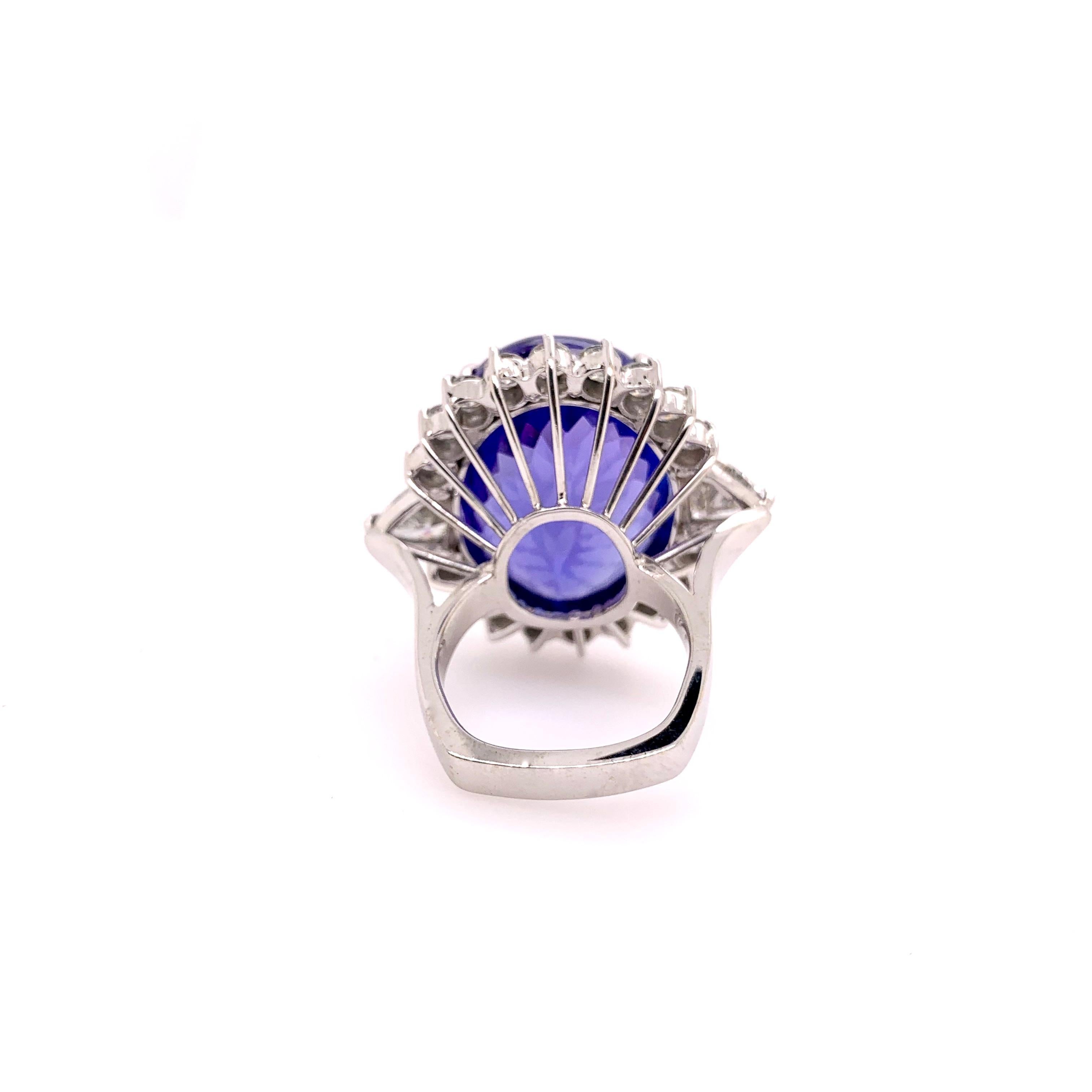 Stunning 18k white gold tanzanite ring with generous size diamonds to compliment the gigantic center stone.  The oval tanzanite weighs 50.33 cts. and is top quality with amazing red and purple flashes.  The side has two 1.00 ct trillion diamonds on