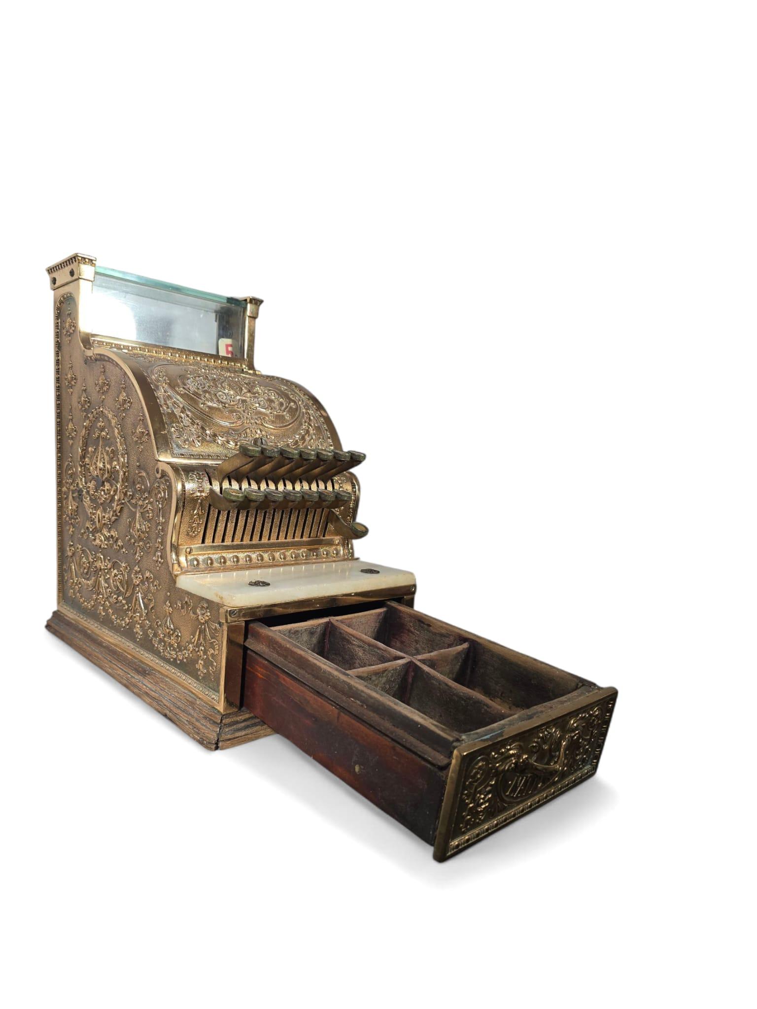 Une caisse enregistreuse antique exceptionnelle, finement travaillée en bronze doré et richement ornée de sculptures en relief complexes. Cette pièce illustre le style opulent et la maîtrise artisanale associés à la National Cash Register Company,