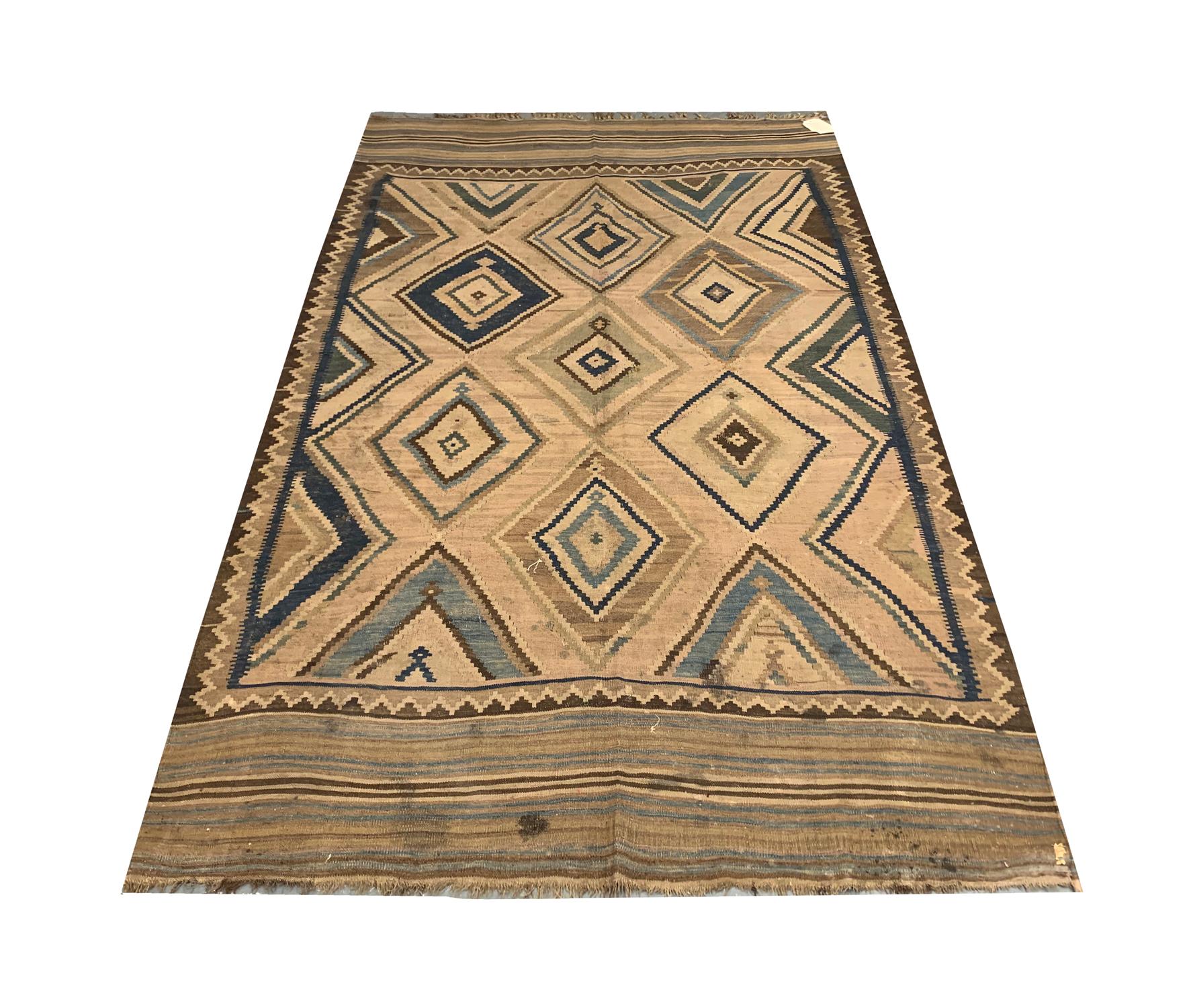 This geometric area rug is a fine wool kilim woven by hand in the 1890s. Featuring a bold diamond geometric design through the centre woven in accents of blue and brown on a subtle cream/beige background. This is then framed by a zig-zag and stripe